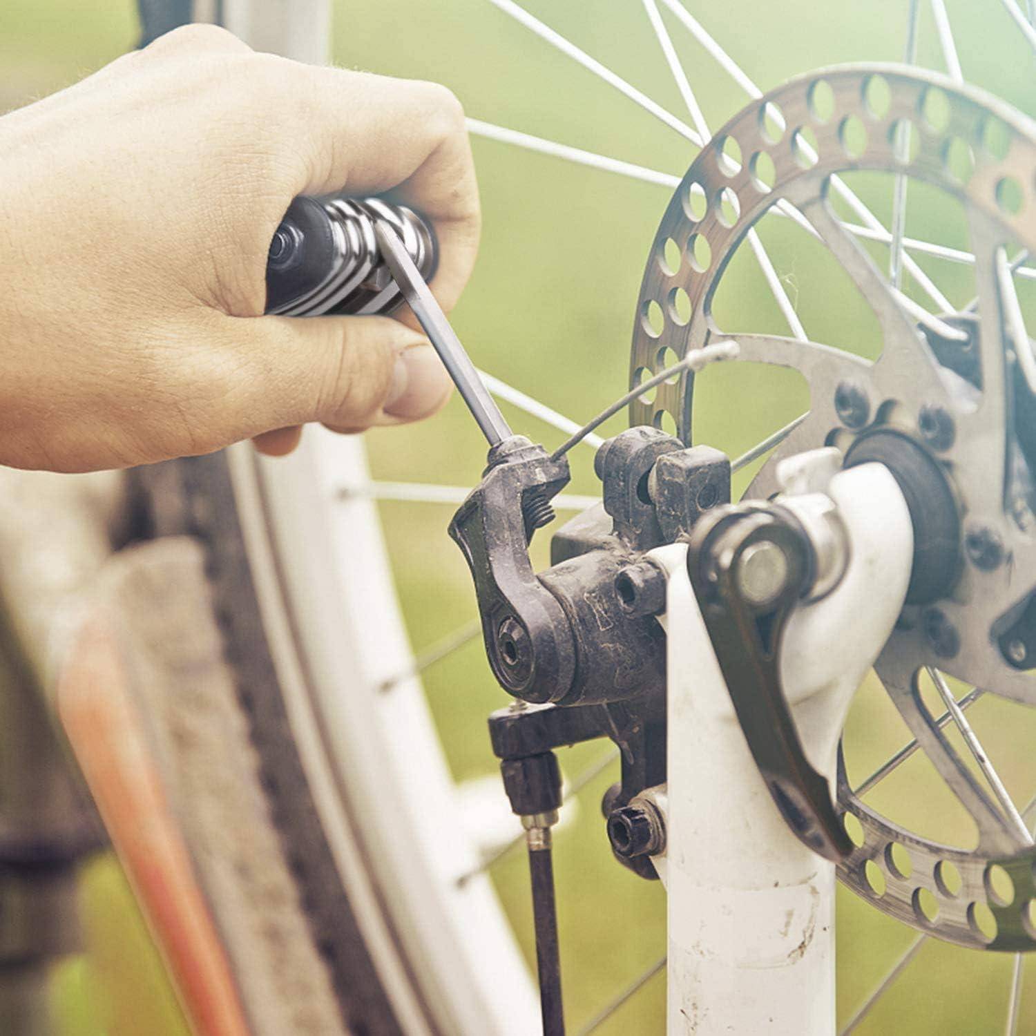 Handstraffung einer Fahrrad-Scheibenbremse mit einem Werkzeug in der Nähe der Bremsscheibe und Speichen.