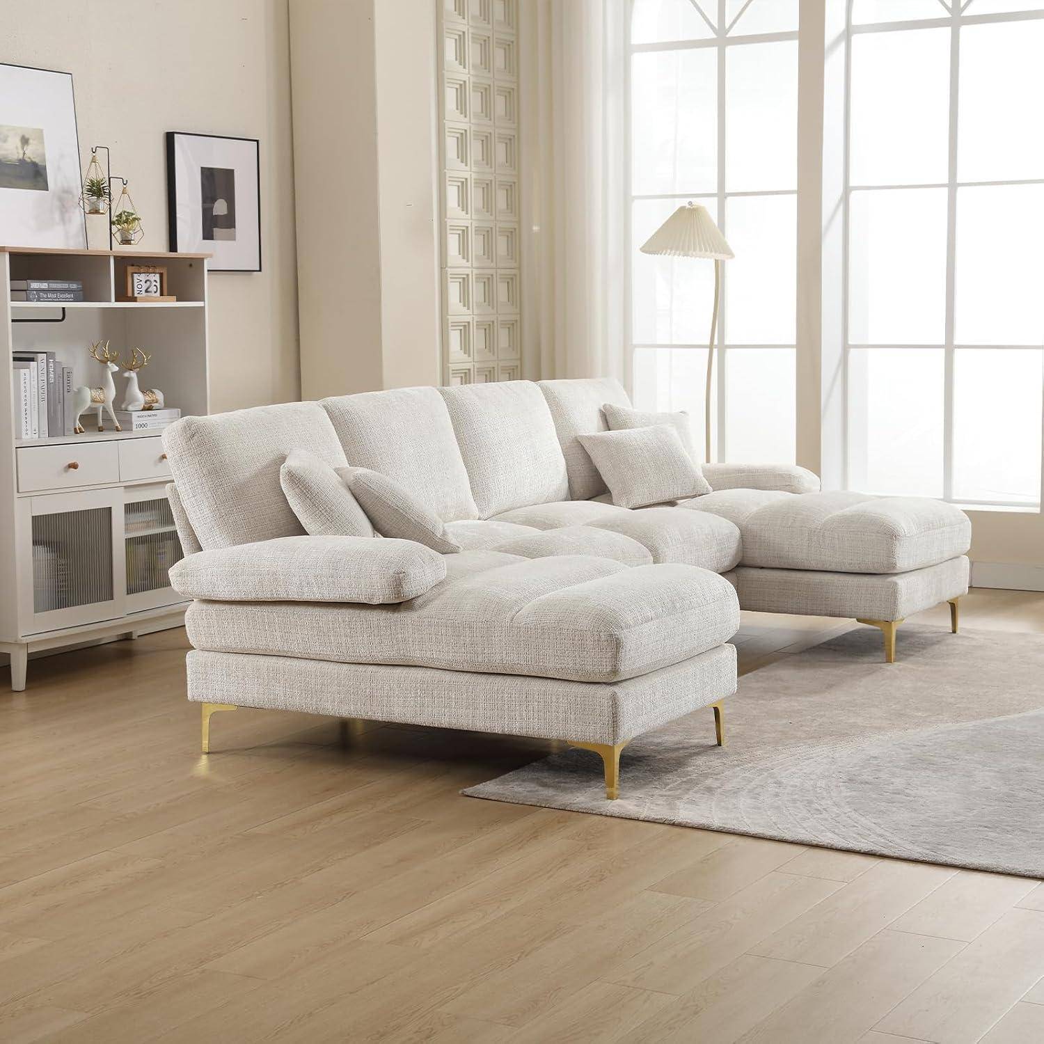 Hellbeige Ecksofa mit Chaiselongue in einem hellen Wohnzimmer, dargestellt mit Kissen auf einem hellen Teppich neben großen Fenstern.