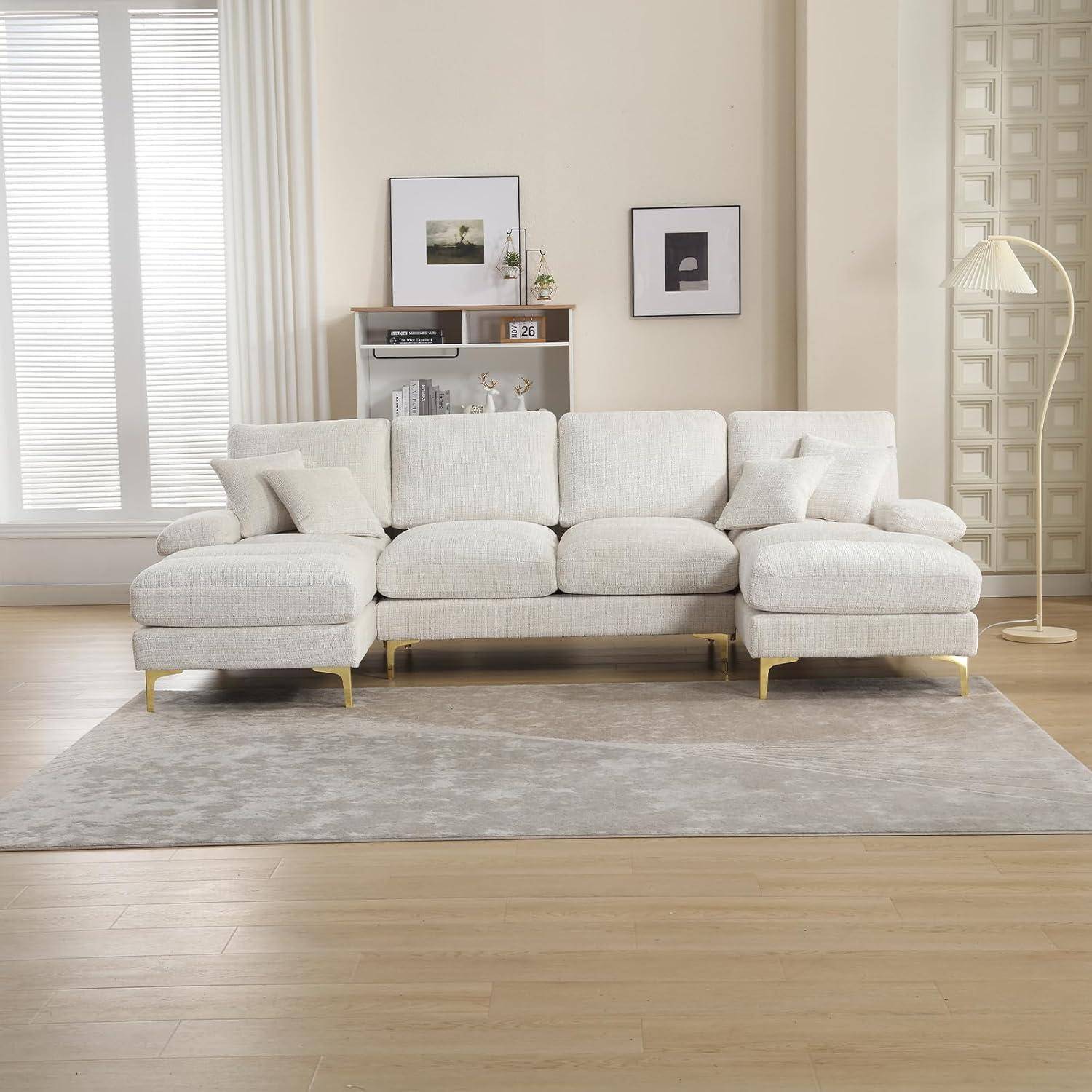 Hellbeige Ecksofa mit Chaiselongue in einem minimalistischen Wohnzimmer, auf einem grauen Teppich mit Wandkunst, Regal und Stehleuchte.