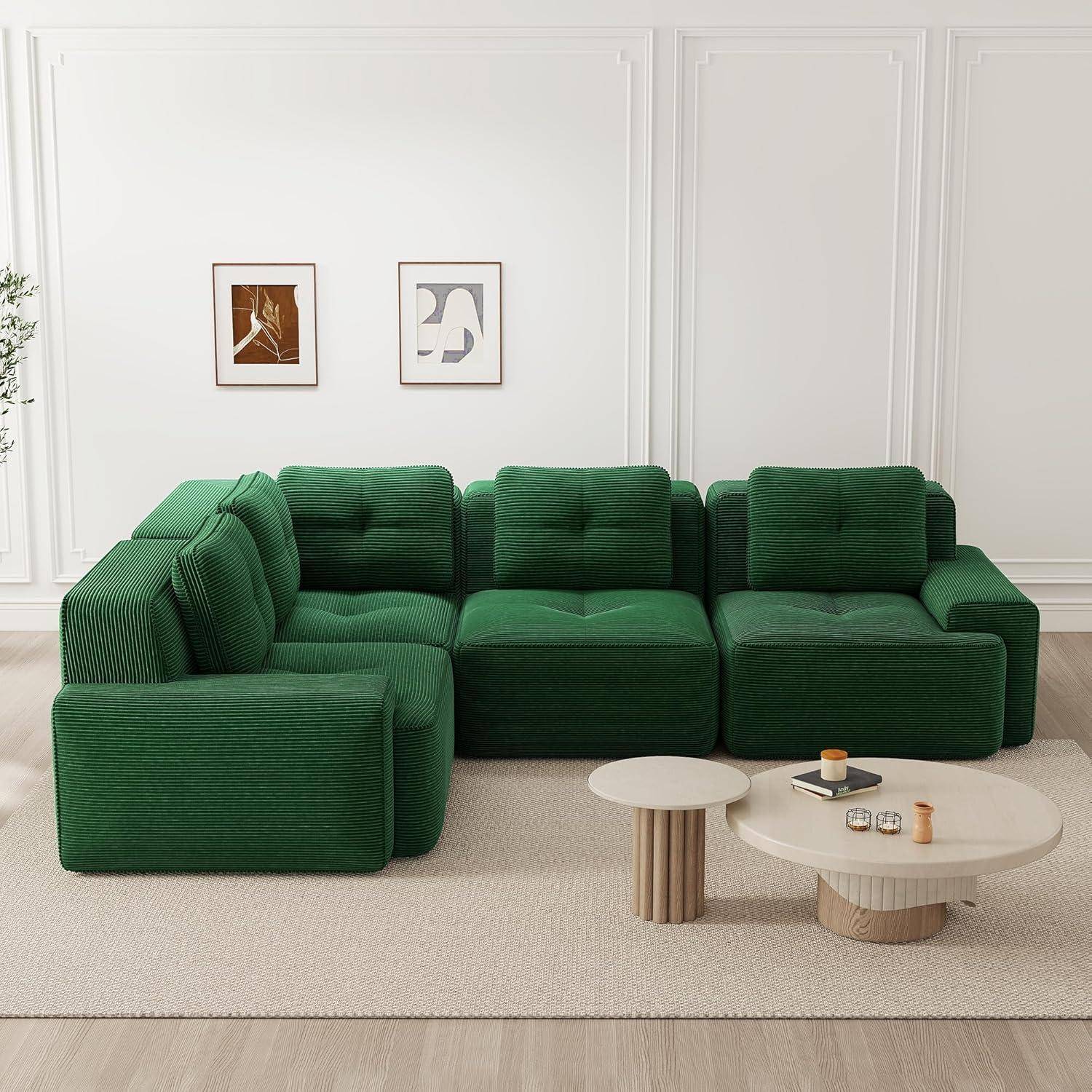 Modernes Wohnzimmer mit grünem modularem Ecksofa, zwei abstrakten Wanddrucken und zwei kleinen runden Couchtischen auf einem hellen Teppich.