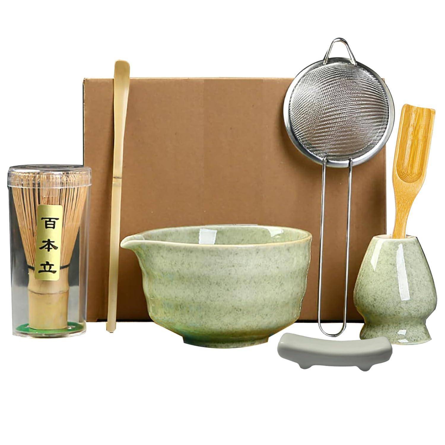 Japanisches Teezeremonie-Set mit Matcha-Schale, Bambusbesen und Löffel, Sieb, Tasse und Kartonverpackung auf weißem Hintergrund
