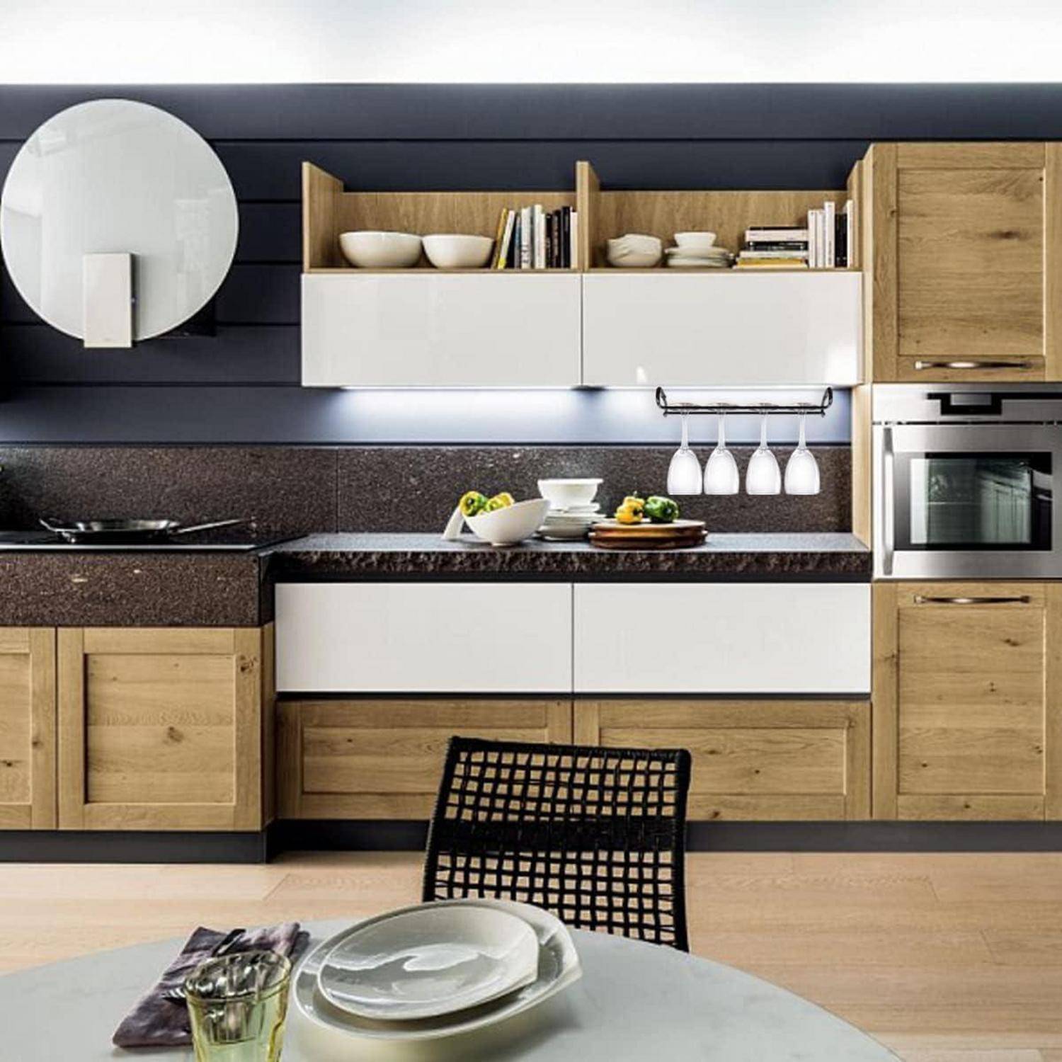 Moderne Küche mit Holz- und weißen Schränken, dunklen Arbeitsplatten, wandmontierter Dunstabzugshaube, eingebautem Backofen, offenen Regalen und einem Tisch mit Geschirr im Vordergrund.
