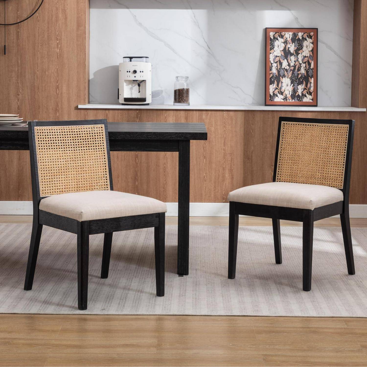 Zwei Stühle mit gewebtem Rücken flankieren einen schwarzen Tisch in einer modernen Küche oder Essecke mit Holzverkleidung und einer Rückwand im Marmor-Look.