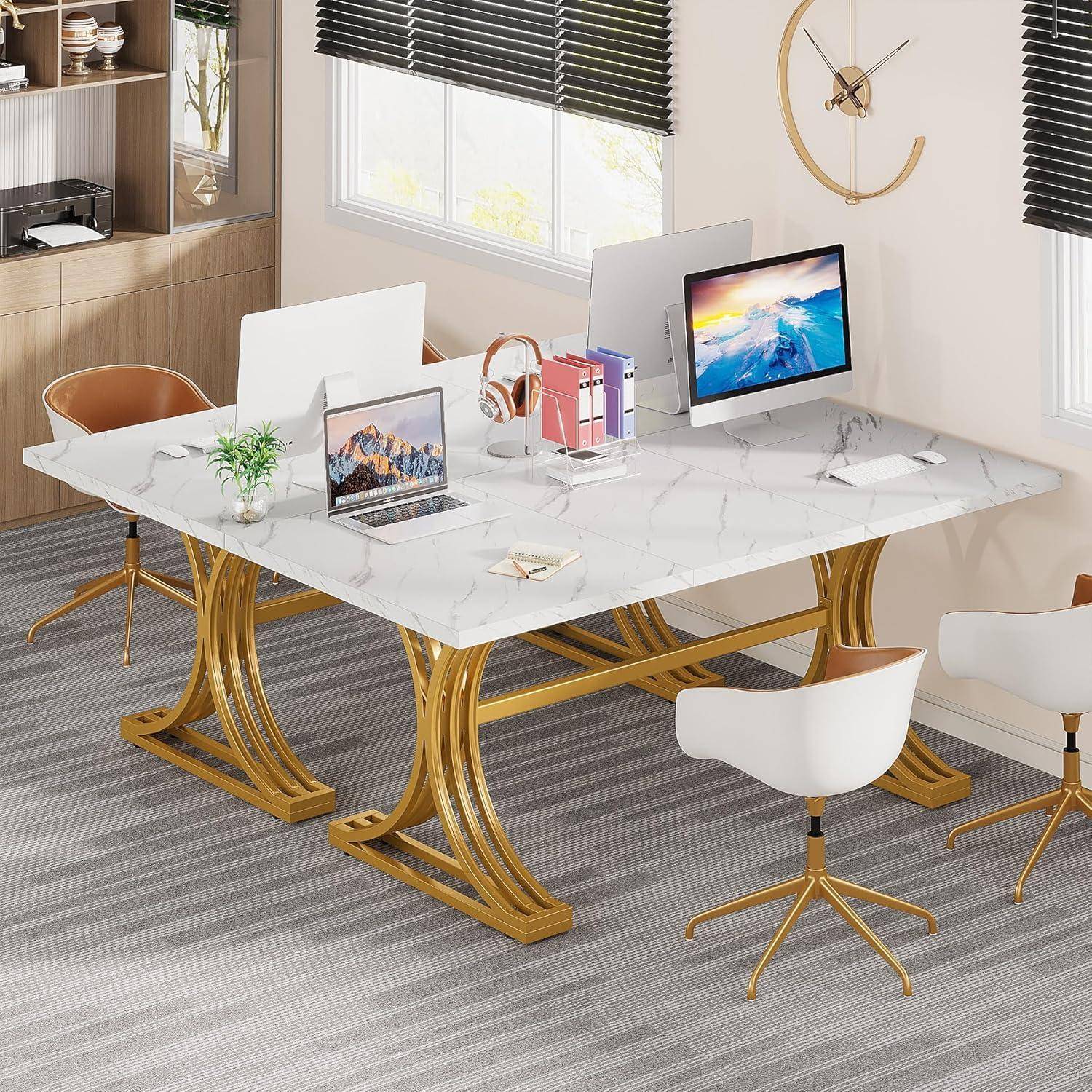 Modernes Homeoffice mit weißem Marmor-Konferenztisch, goldenem Sockel, vier Stühlen, zwei Schreibtischmonitoren, einem Laptop und Büromaterialien neben einem Fenster.