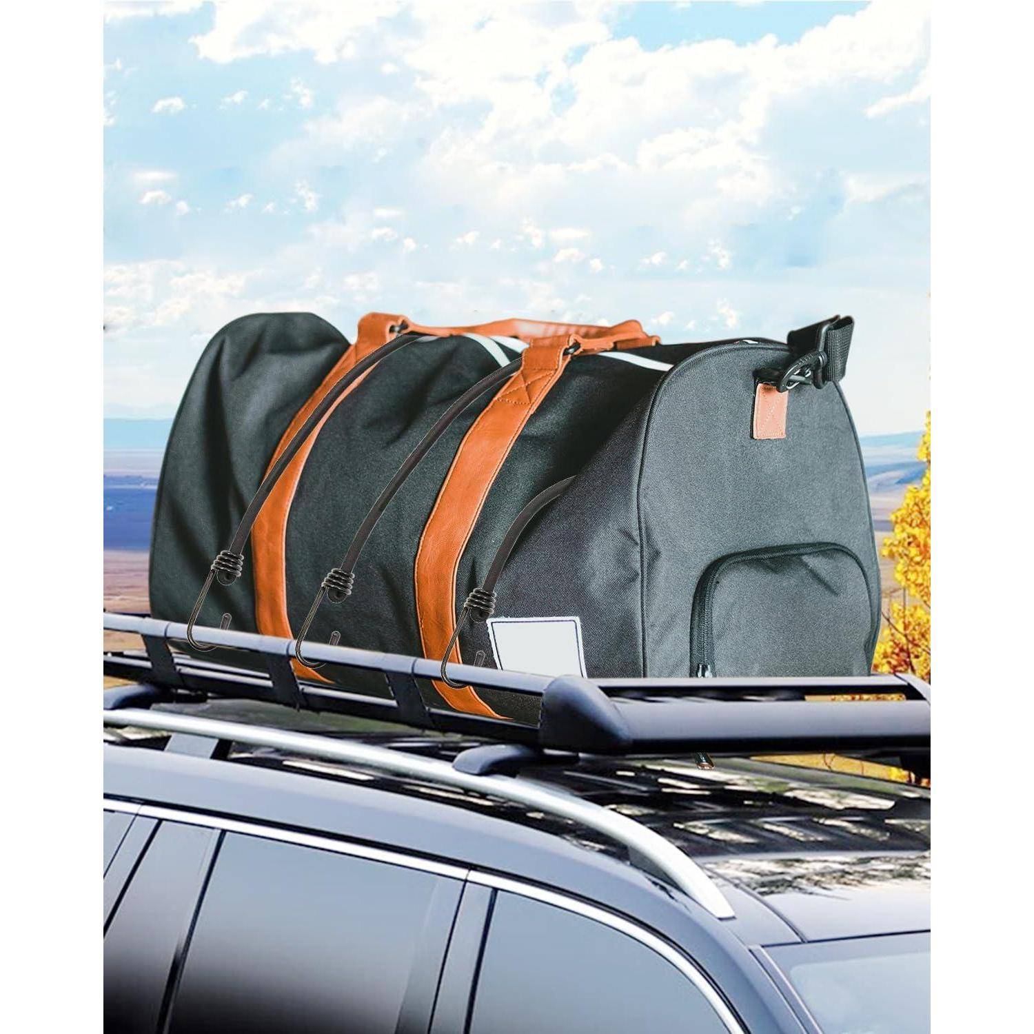 Graue und orangefarbene Reisetasche auf einem Autodachträger befestigt, mit einem malerischen Himmel im Hintergrund.