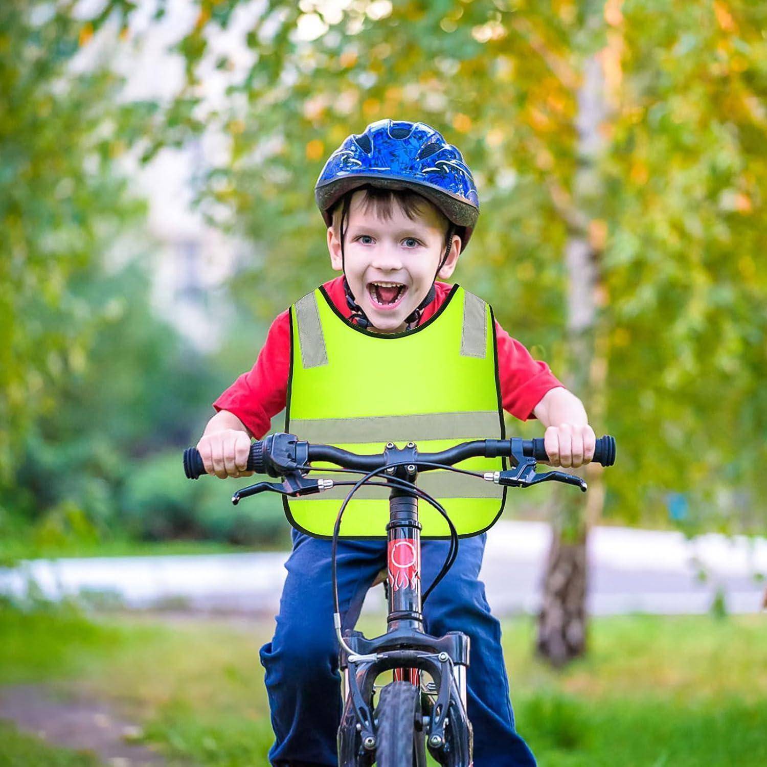 Ein lächelnder junger Junge, der einen Helm und eine Sicherheitsweste trägt, fährt ein Fahrrad im Freien in einem Park.