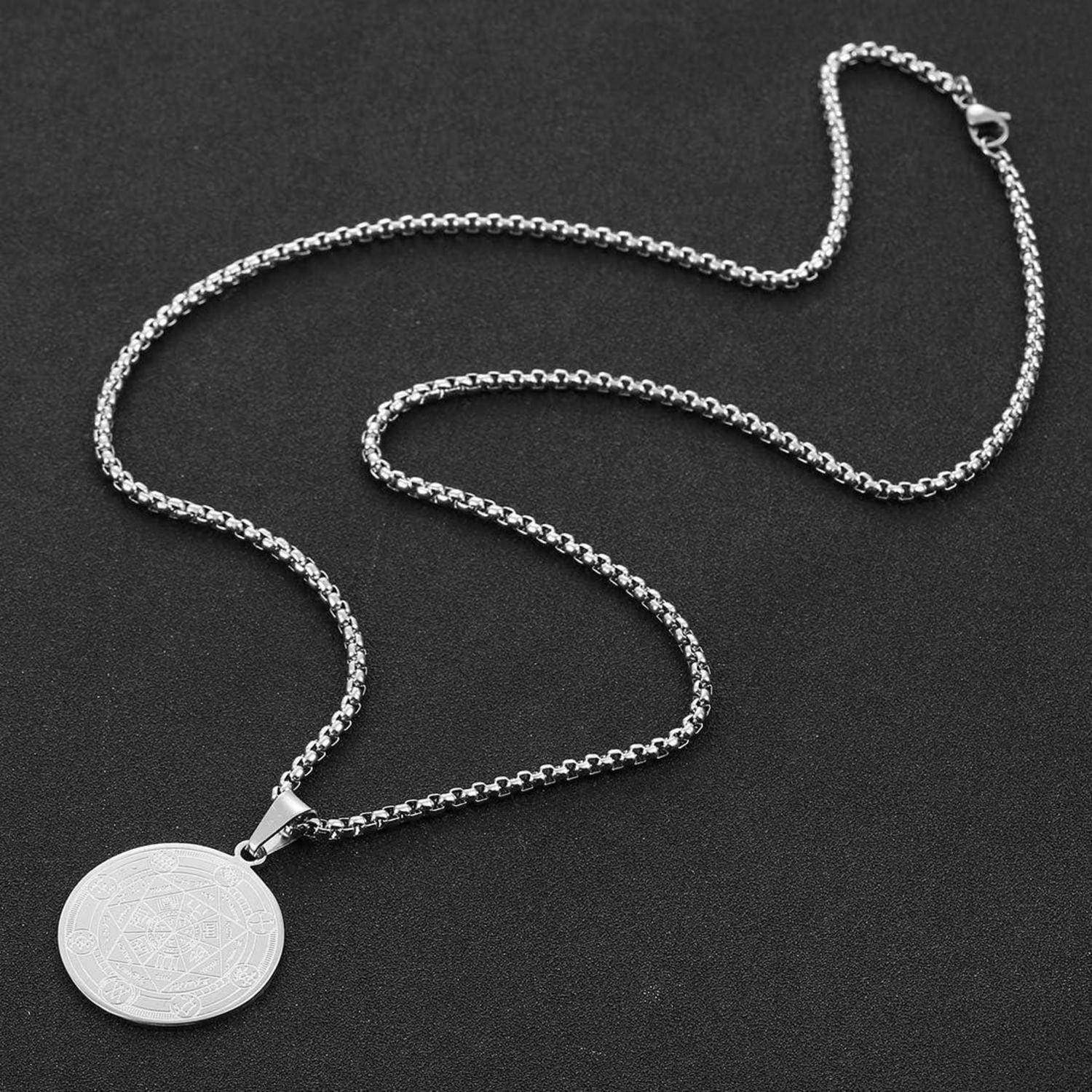 Silberkettenhalsband mit rundem graviertem Anhänger auf dunklem Hintergrund.