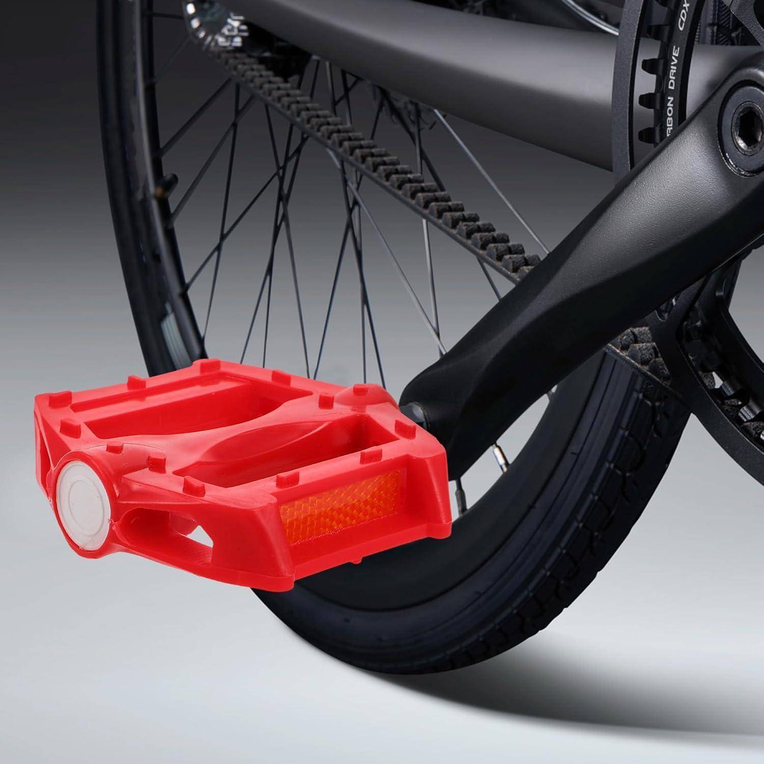 Nahaufnahme eines Fahrradpedals mit einem leuchtend roten Reflektor, befestigt an einem schwarzen Fahrradreifen und Rahmen.