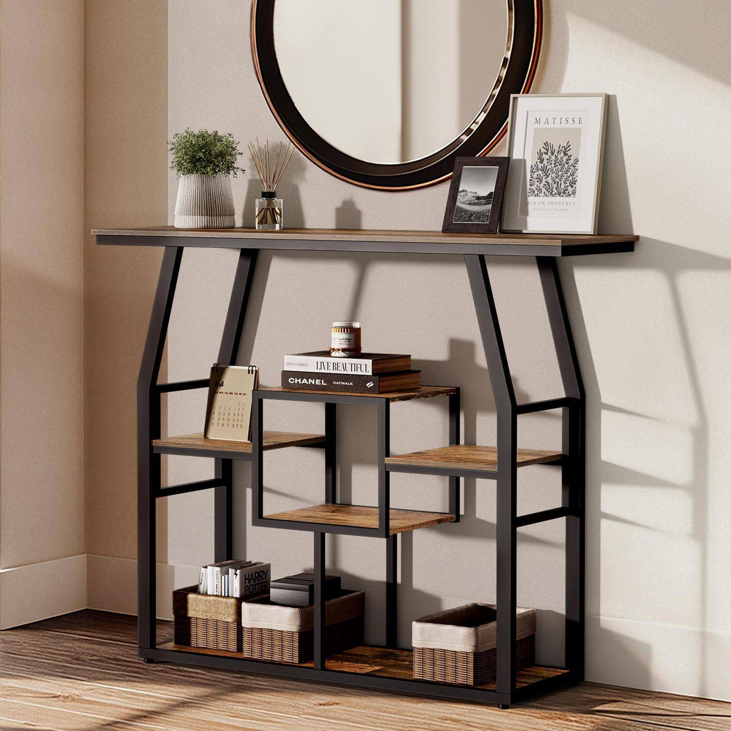 Moderner schwarz-metallischer Konsolentisch aus Holz mit rundem Spiegel darüber, dekoriert mit Pflanzen, gerahmter Kunst, Büchern und Aufbewahrungskörben vor einer hellen Wand.