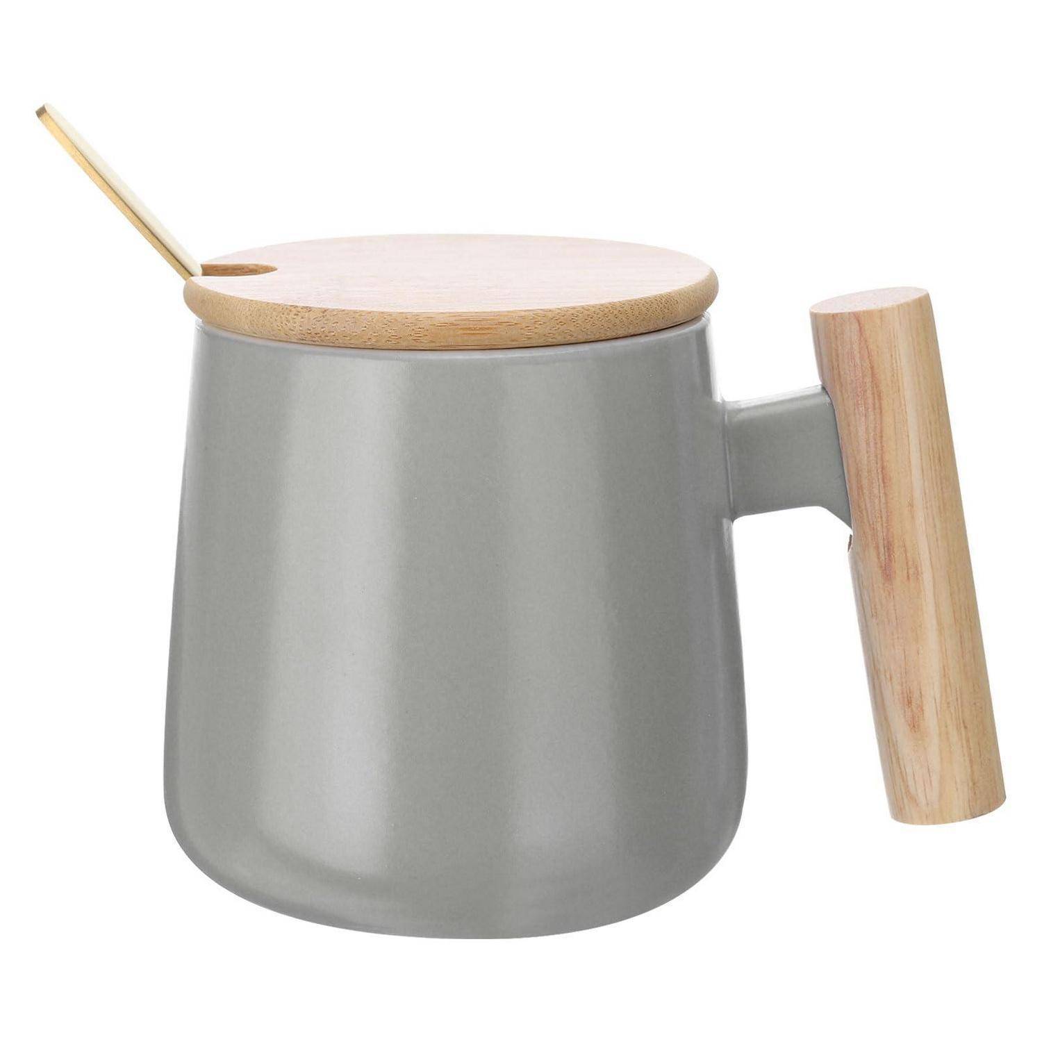 Grauer Keramikbecher mit einem hellen Holzdeckel und Griff, mit einem goldenen Löffel, der in der Deckelöffnung ruht.