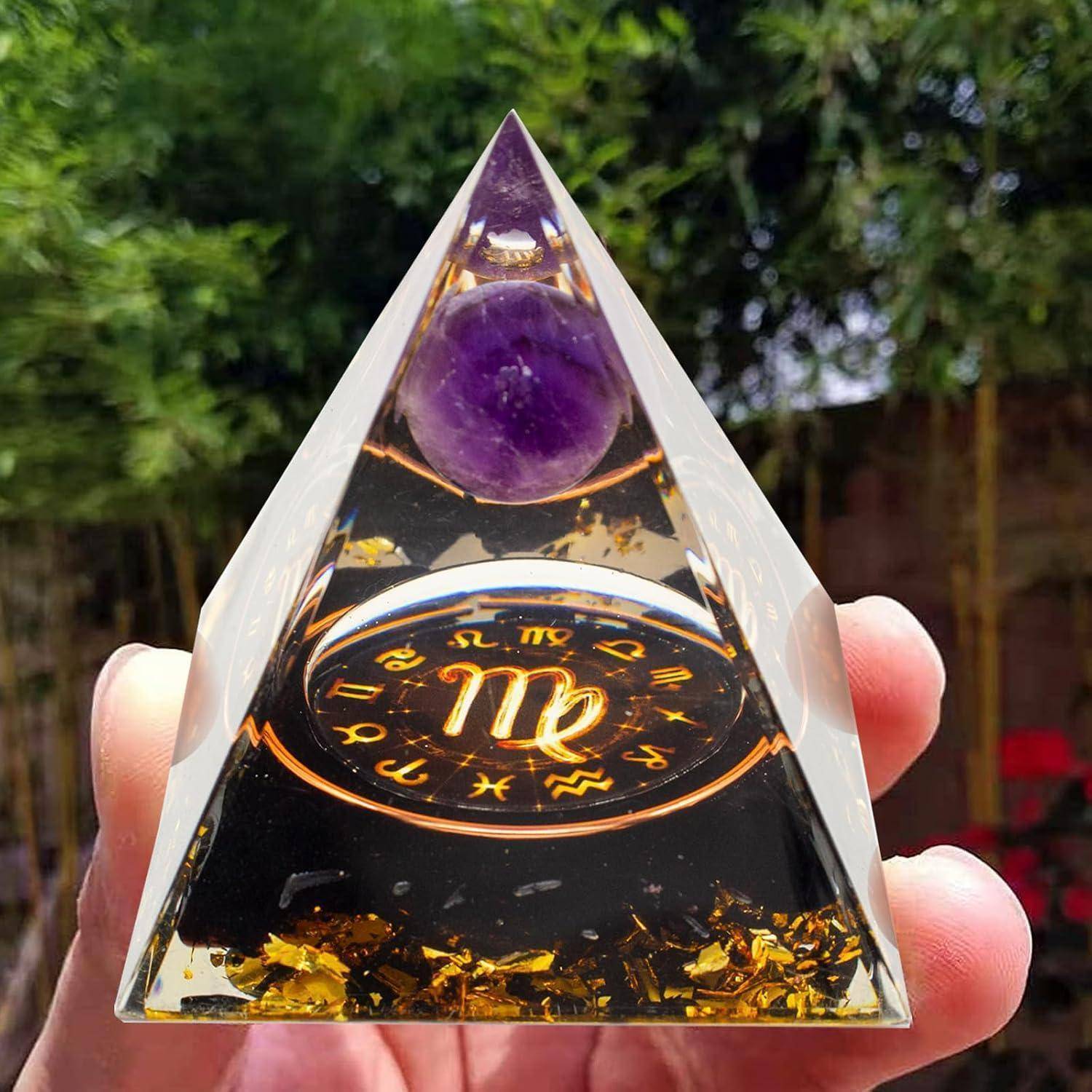 Hand hält einen klaren Pyramiden-Briefbeschwerer mit einer Amethyst-Kugel und Goldflöckchen im Inneren, mit einem Tierkreiszeichen in der Mitte.