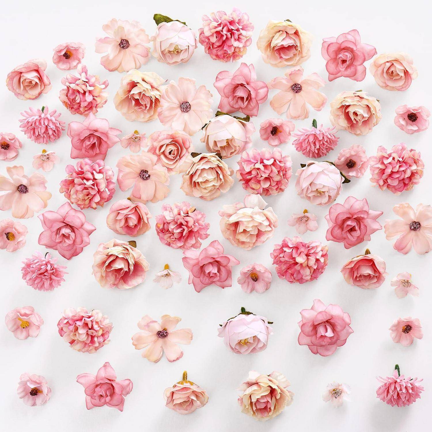 Sortierte rosa und pfirsichfarbene Papierblumen, die auf weißem Hintergrund angeordnet sind und ein dekoratives Blumenmuster bilden.