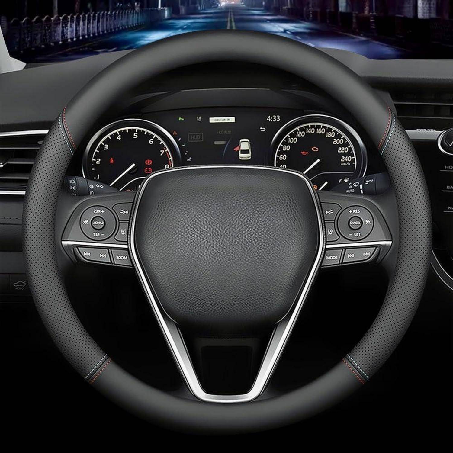 Nahaufnahme eines Autolenkrads mit Armaturenbrett-Anzeigen und zentralem digitalen Display, das dahinter sichtbar ist.