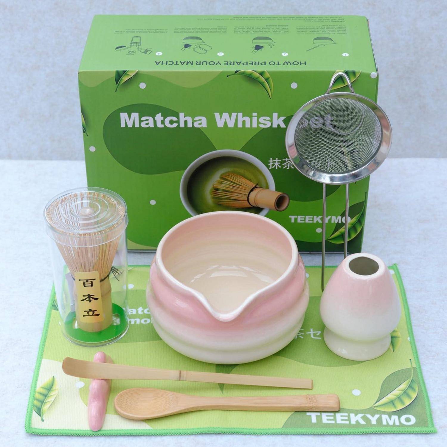 Matcha-Schneebesen-Set mit grüner Geschenkbox, keramischer Teeschale und Schneebesen-Halter, Bambus-Schneebesen, Löffel, Sieb und Tee-Utensilien-Matte zum Zubereiten von Matcha angeordnet.