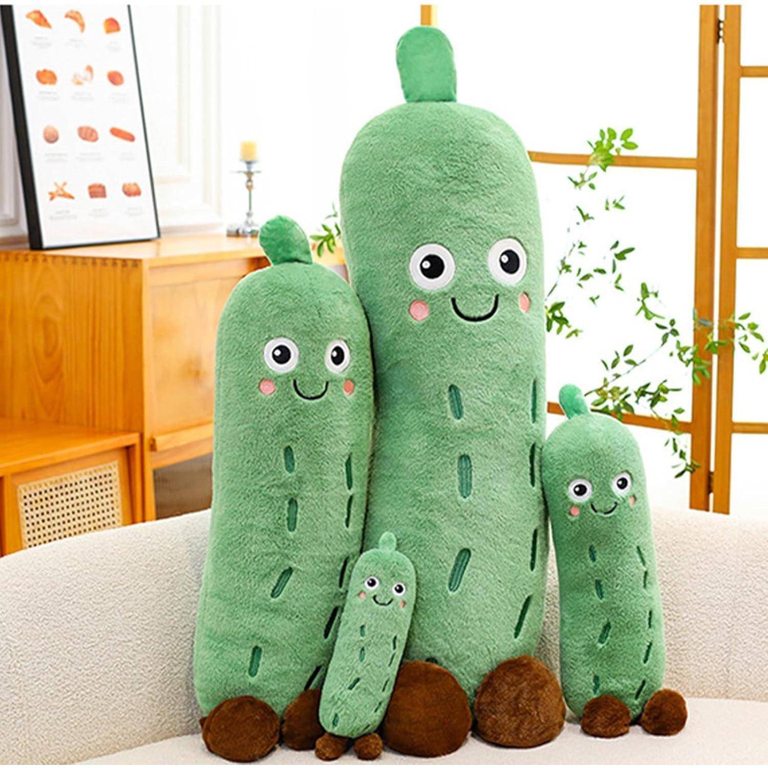Vier grüne, kaktusförmige Plüschtiere in verschiedenen Größen mit lachenden Gesichtern sitzen auf einem Sofa in einem hellen Wohnzimmer.