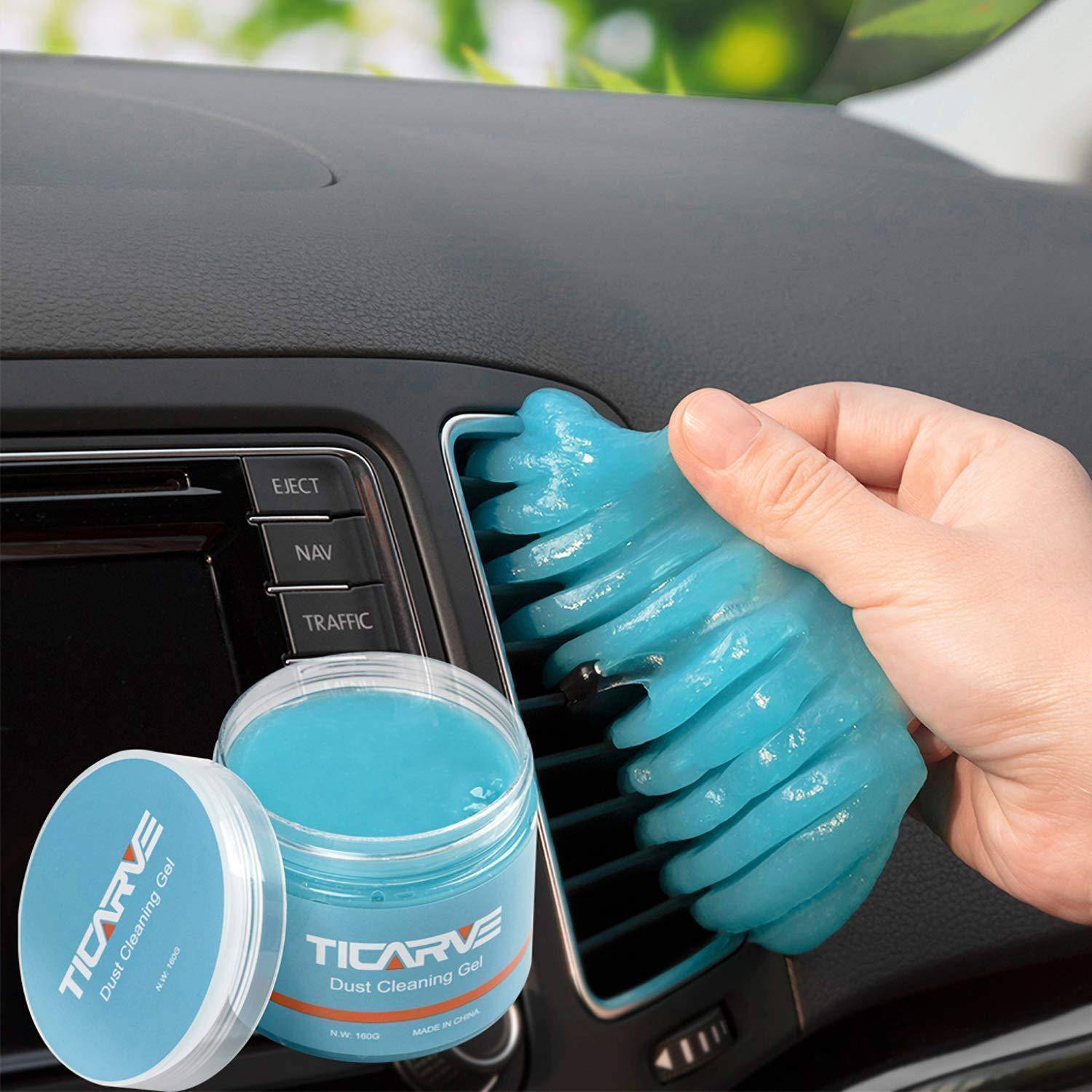 Eine Hand verwendet blauen Gel-Staubreiniger, um Staub aus einem Autolüftungsgitter zu entfernen, mit einem Glas „TICARVE Dust Cleaning Gel