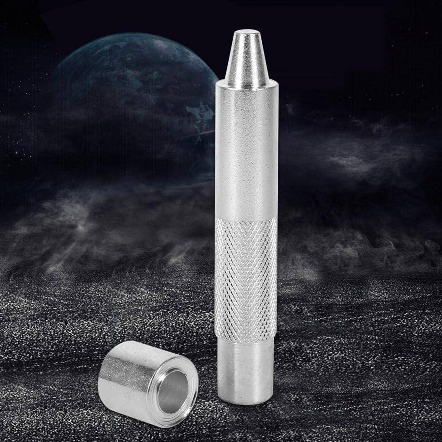 Metallisches zylindrisches Werkzeug mit gerilltem Griff und konischer Spitze, aufrecht neben einer passenden Kappe auf dunklem, strukturiertem Hintergrund dargestellt.