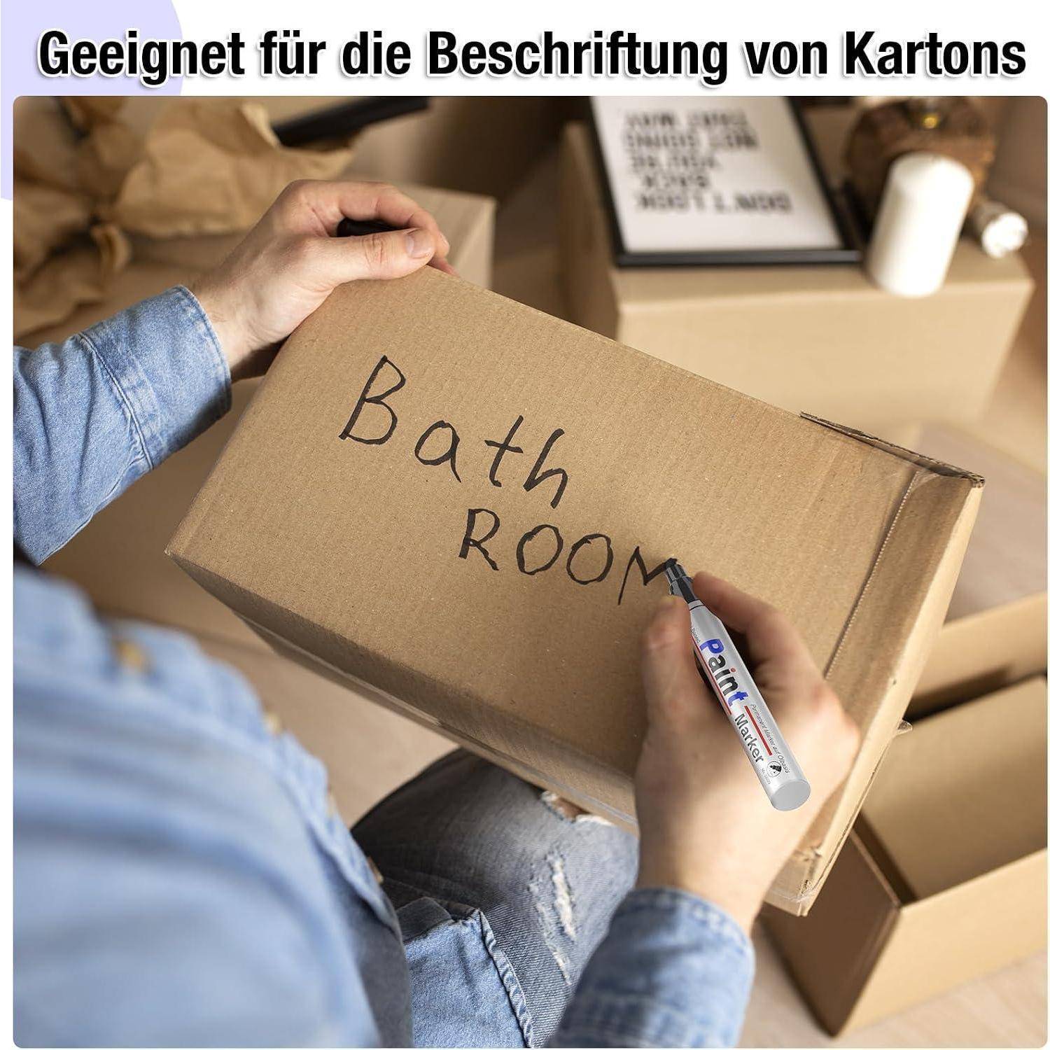 Person beschriftet einen Pappumzugskarton mit 