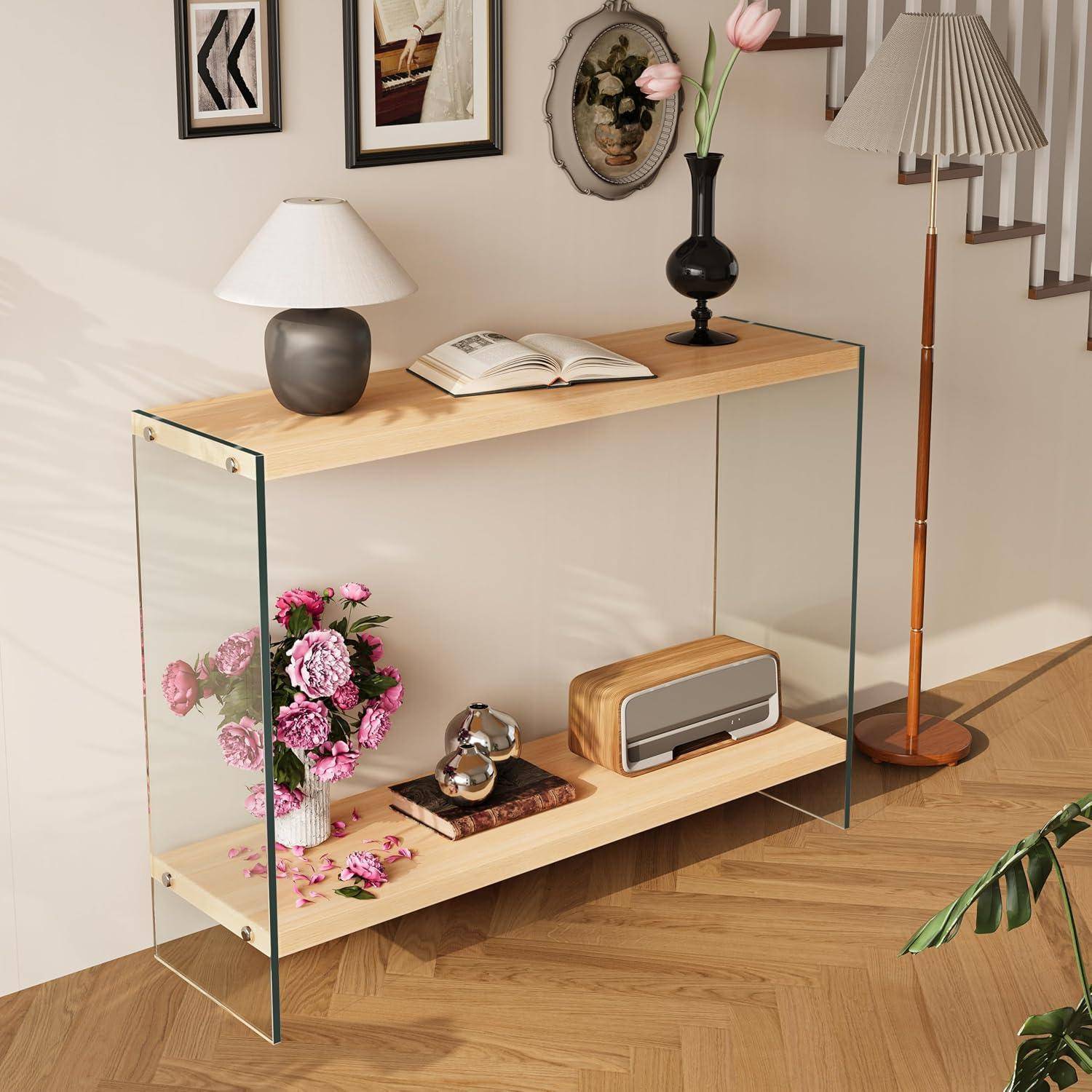 Moderner Konsolen-Tisch aus Glas und Holz in einem Raum, stilvolles Arrangement mit Lampen, Blumen, Büchern und Dekoration neben einer Treppe.