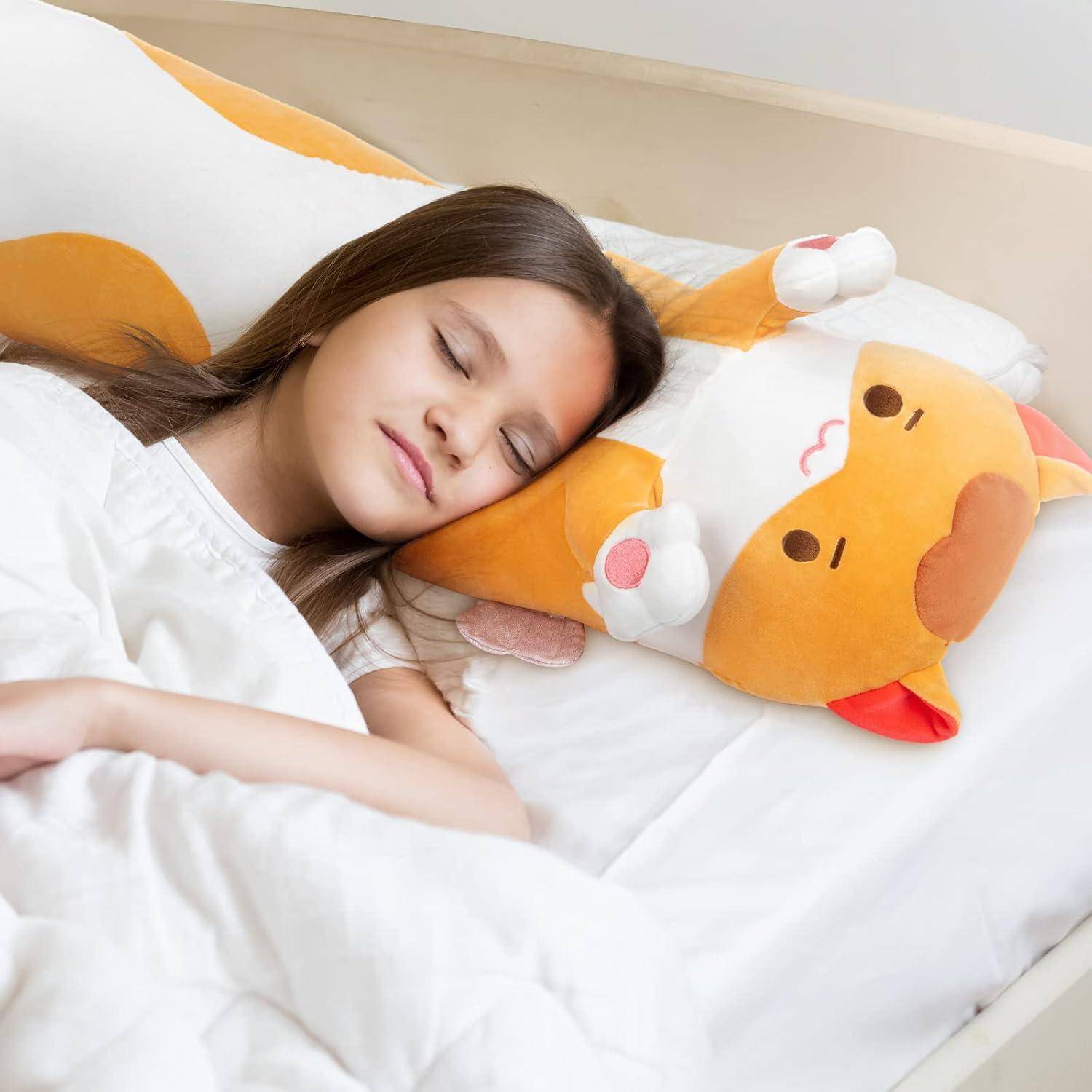 Ein junges Mädchen schläft im Bett und ruht sich neben einem großen orange-weißen Plüsch-Katzenkissen aus.