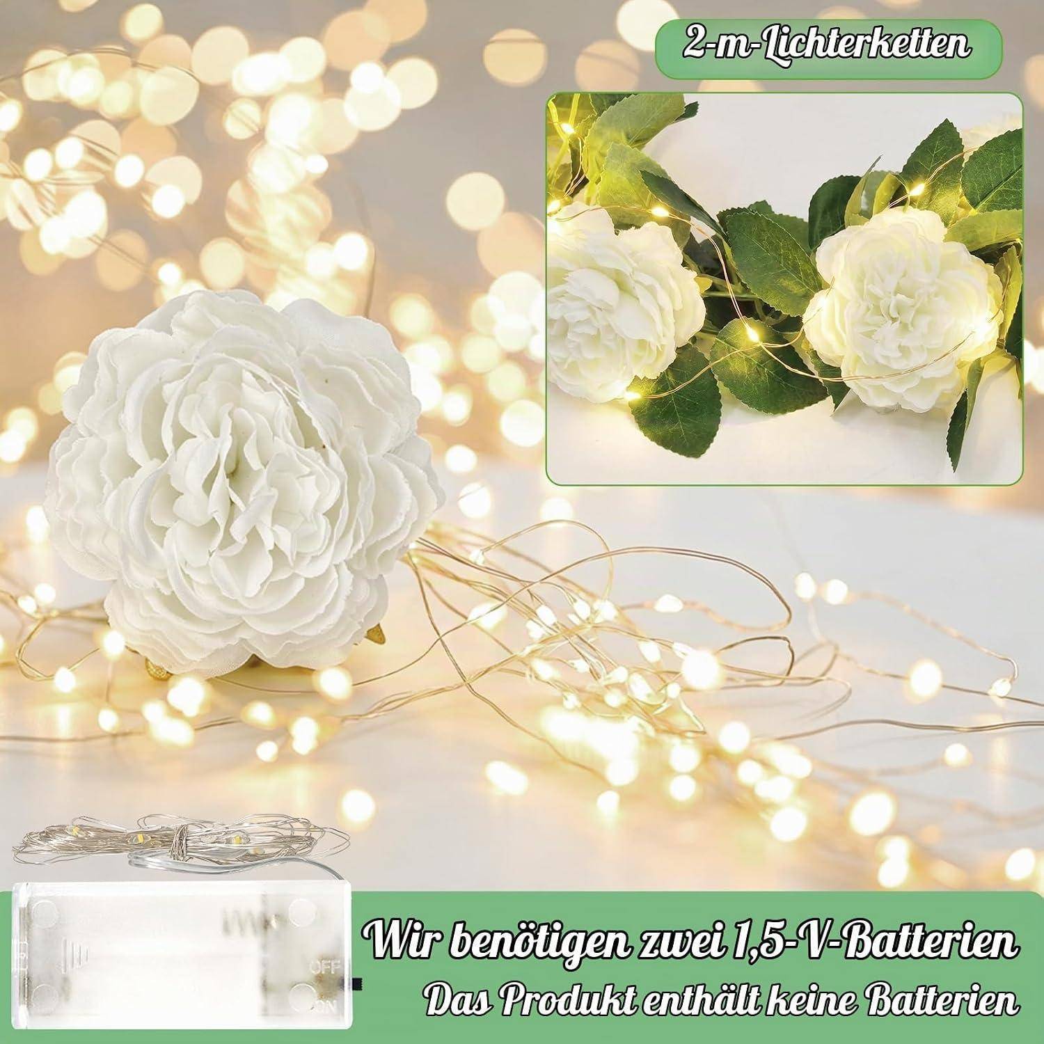 Weiße künstliche Blume mit warmweißen Feenlichtern; die Vergrößerung zeigt eine 2 m lange Lichtgirlande um die Blumen. Der deutsche Text besagt, dass zwei 1,5-V-Batterien erforderlich sind, nicht enthalten.