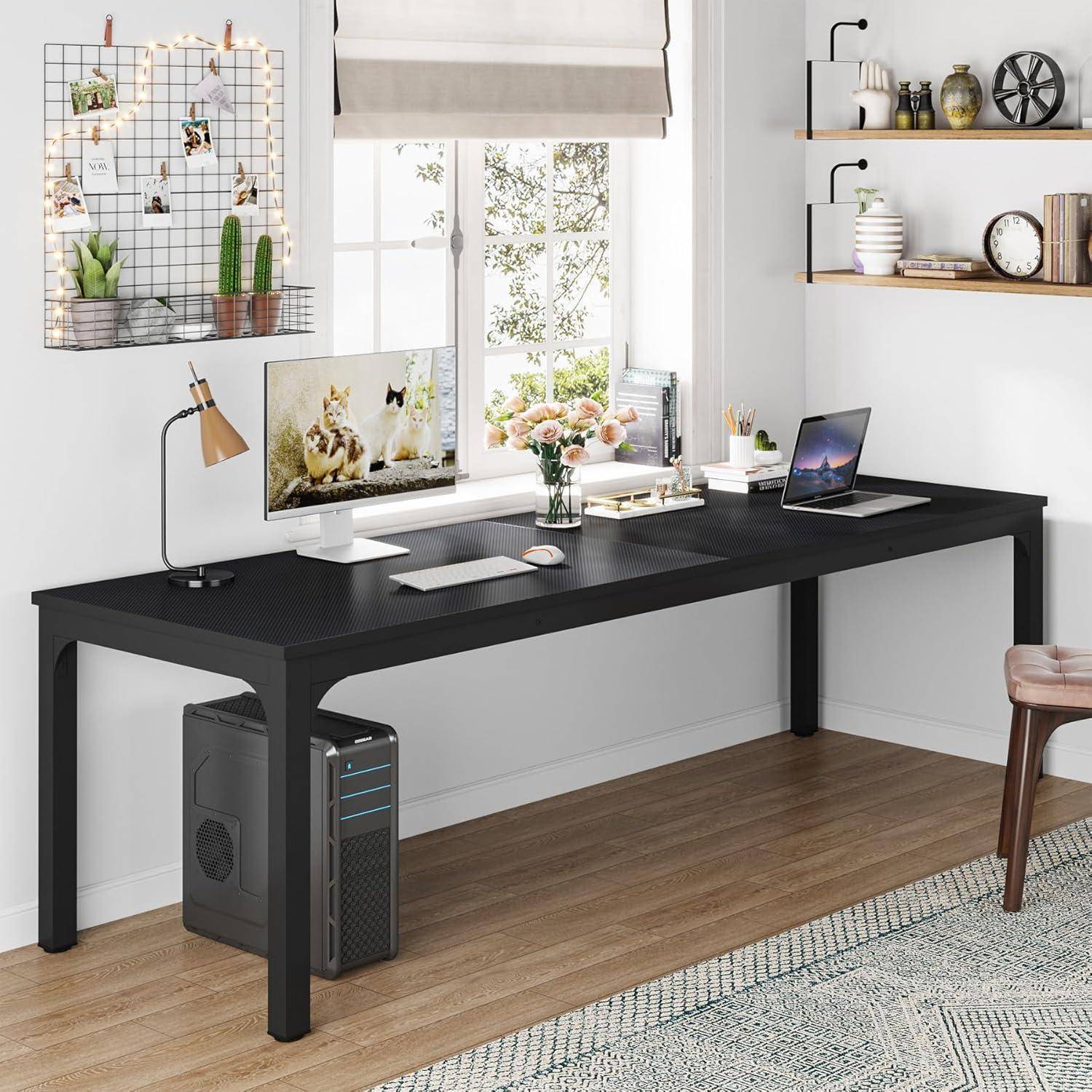 Modernes Homeoffice mit einem schwarzen L-förmigen Schreibtisch, auf dem ein Monitor, ein Laptop, eine Lampe und Blumen in der Nähe eines Fensters stehen, mit Wandregalen und Dekoration.