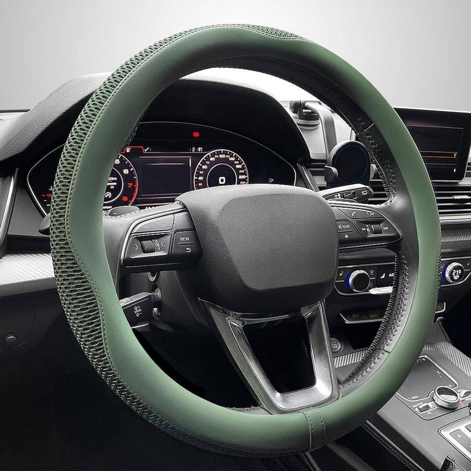 Nahaufnahme eines Autolenkrads mit grüner Abdeckung, die das Armaturenbrett, die Instrumententafel und die Mittelkonsole in einem modernen Fahrzeug zeigt.