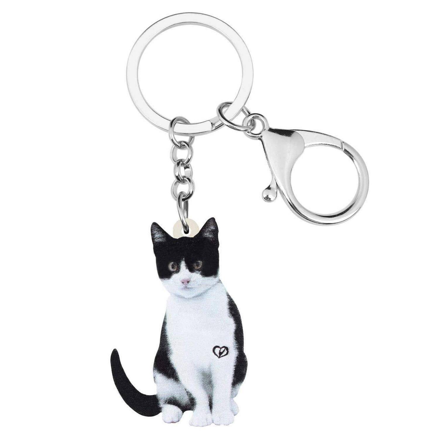 Katzenförmiger Metallanhänger mit schwarzweißem Katzenanhänger, der an einem Splitring und einer Hummerkralle an weißem Hintergrund befestigt ist