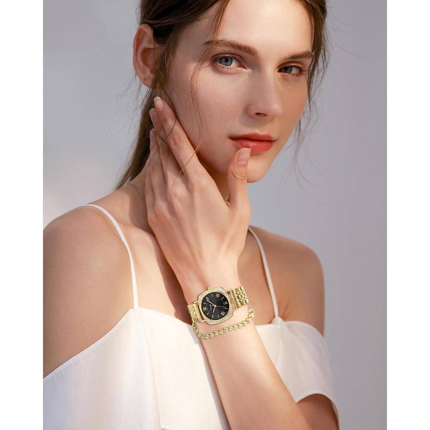 Porträt einer Frau, die eine goldene Armbanduhr und ein Armband trägt, posierend vor einem hellgrauem Hintergrund in einem weißen schulterfreien Oberteil.
