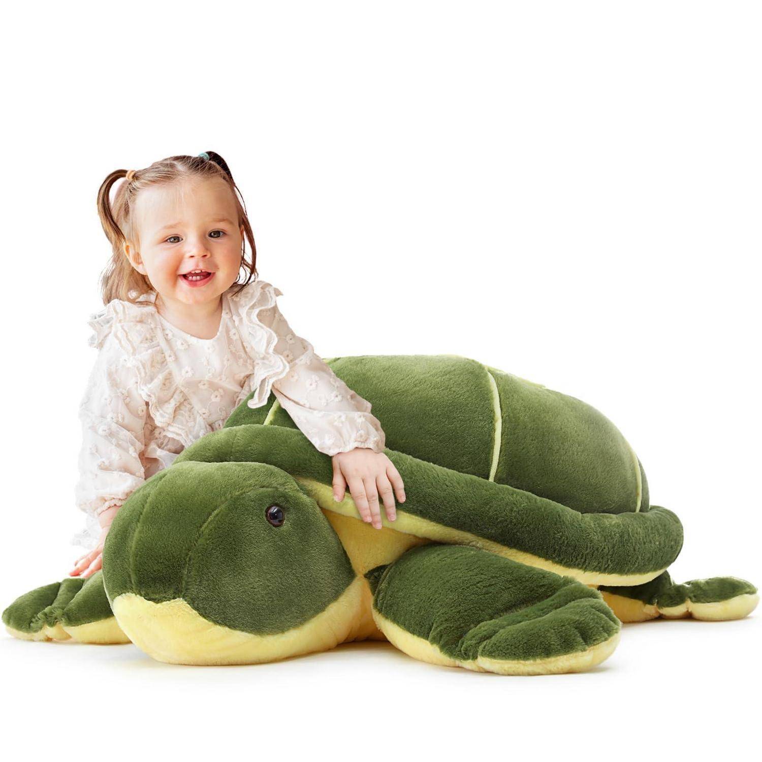 Lächelndes junges Mädchen, das eine große weiche grüne Schildkröte auf weißem Hintergrund umarmt.