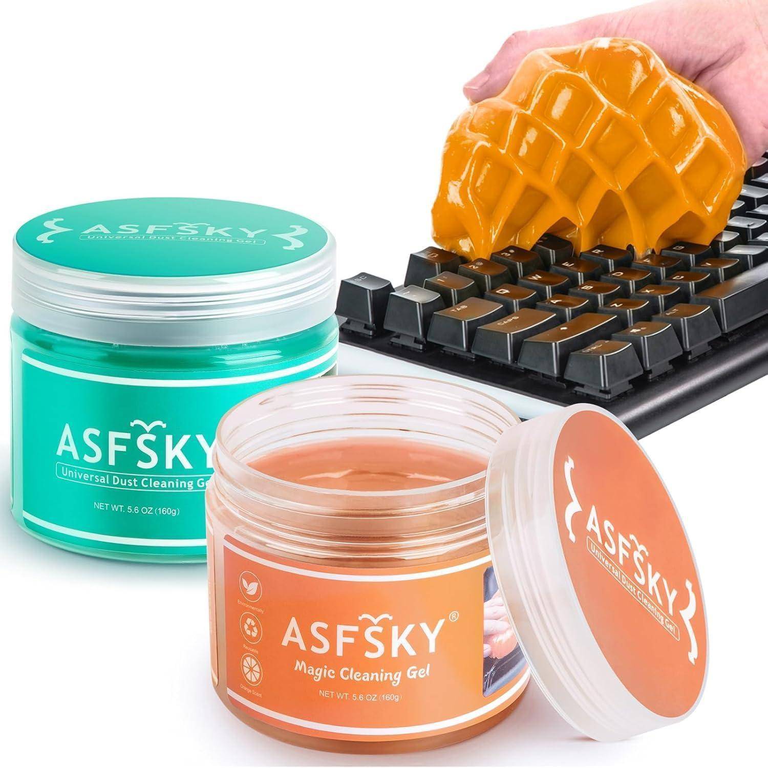 Eine Hand reinigt eine Tastatur mit orangefarbenem Reinigungsgel neben grünen und orangefarbenen ASFSKY-Reinigungsgläsern auf weißem Hintergrund.