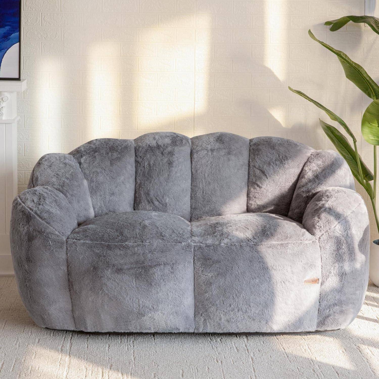 Graues Plüsch-Zweisitzer-Sofa mit abgerundeter, gepolsterter Rückenlehne und Armlehnen in einem sonnendurchfluteten Zimmer