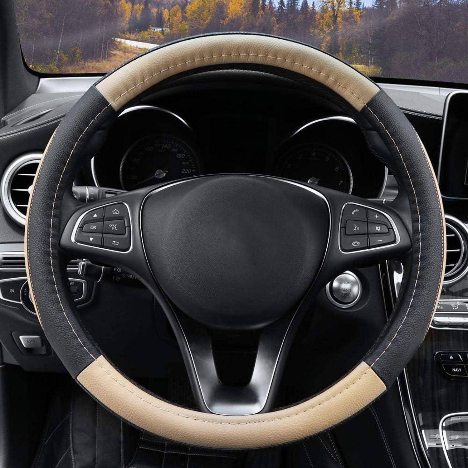 Nahaufnahme eines Autolenkrads mit beigem und schwarzem Bezug, das die Armaturenbrett-Bedienelemente und Instrumente im Fahrzeuginneren zeigt.