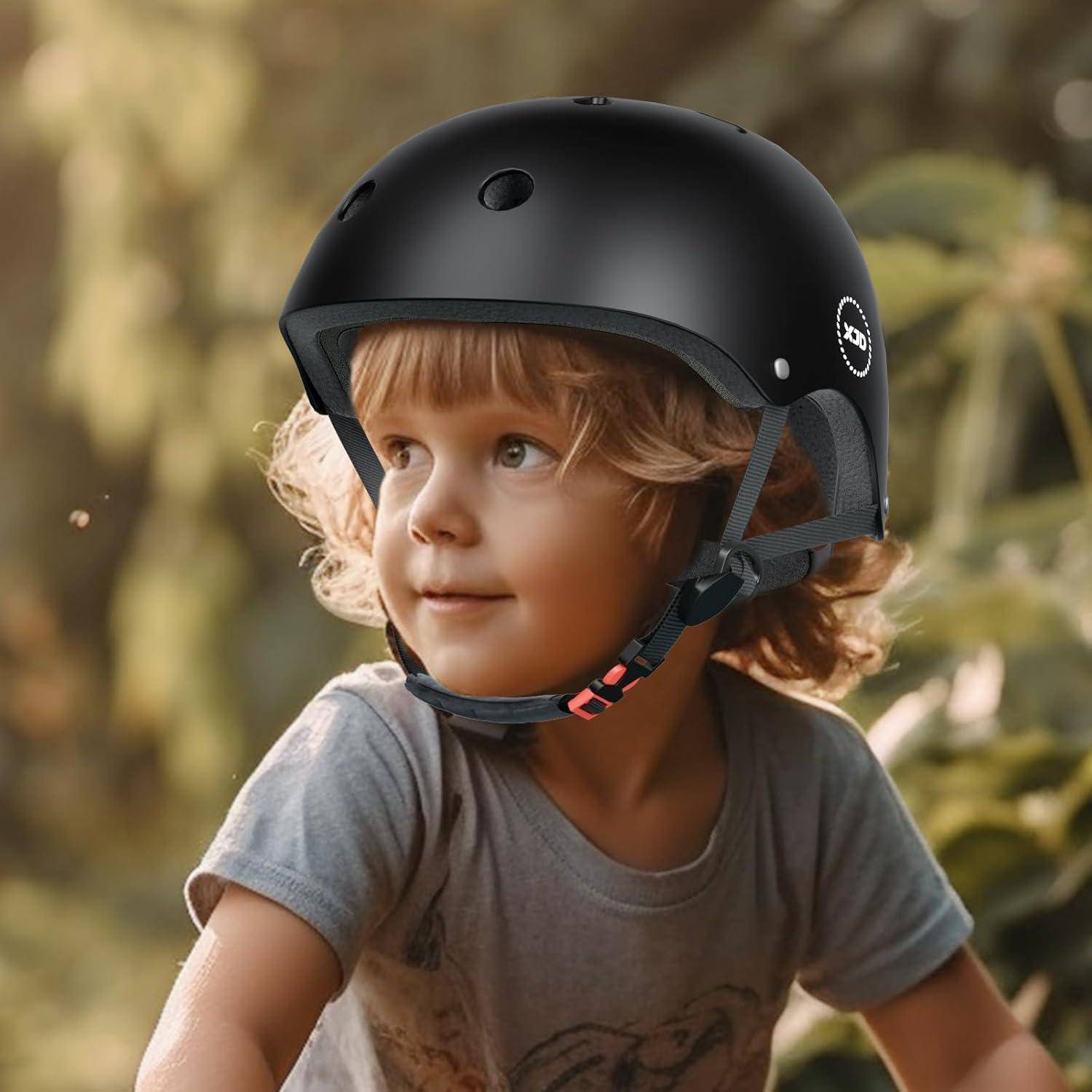 Kleines Kind mit schwarzem Helm im Freien, schaut zur Seite in einer waldigen Umgebung.