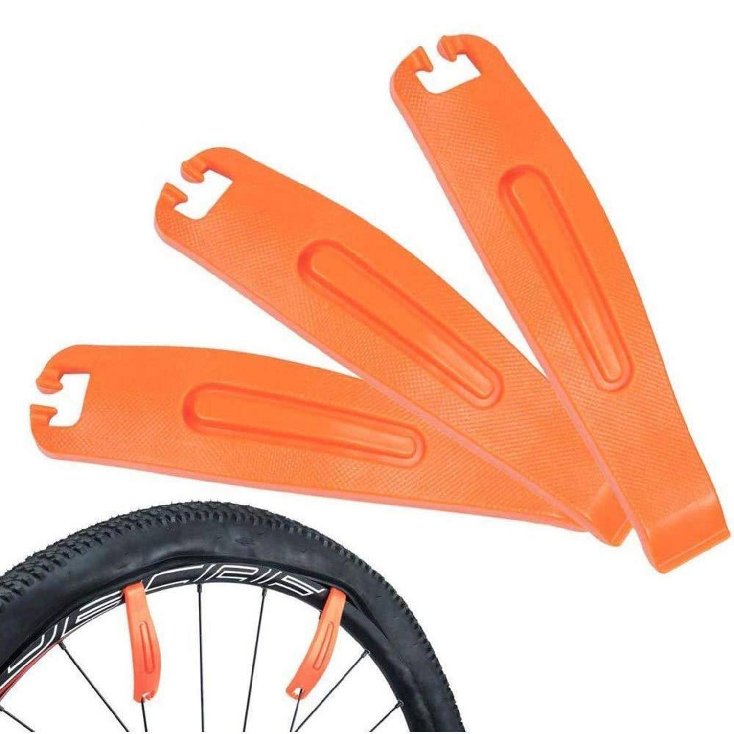 Drei orangefarbene Kunststoff-Reifenheber über einem Fahrradreifen mit zwei Hebeln, die zwischen Reifen und Felge eingeführt sind, um den Reifen zu entfernen.
