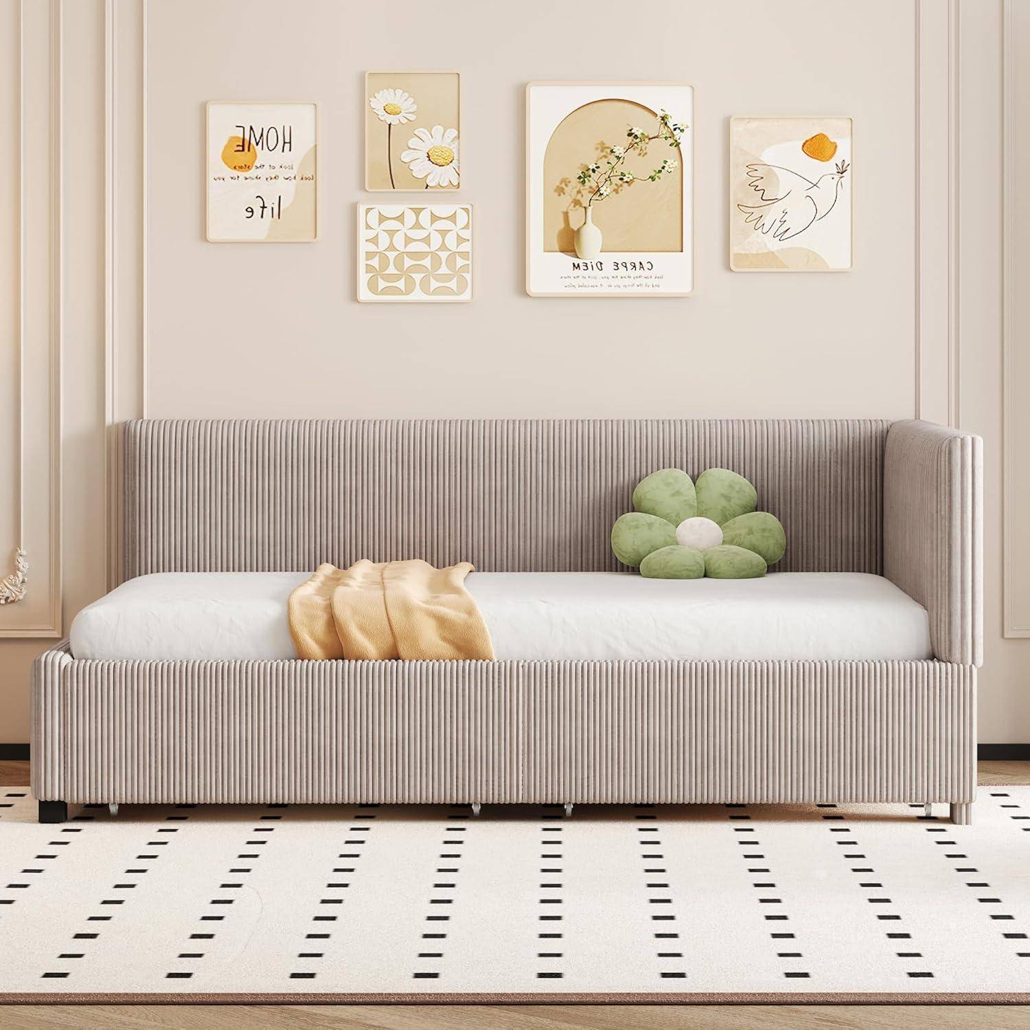 Beiges Kinderzimmer mit einem gestreiften Tagesbett, grünem Blumenkissen und vier pastellfarbenen Wandkunstdrucken darüber.
