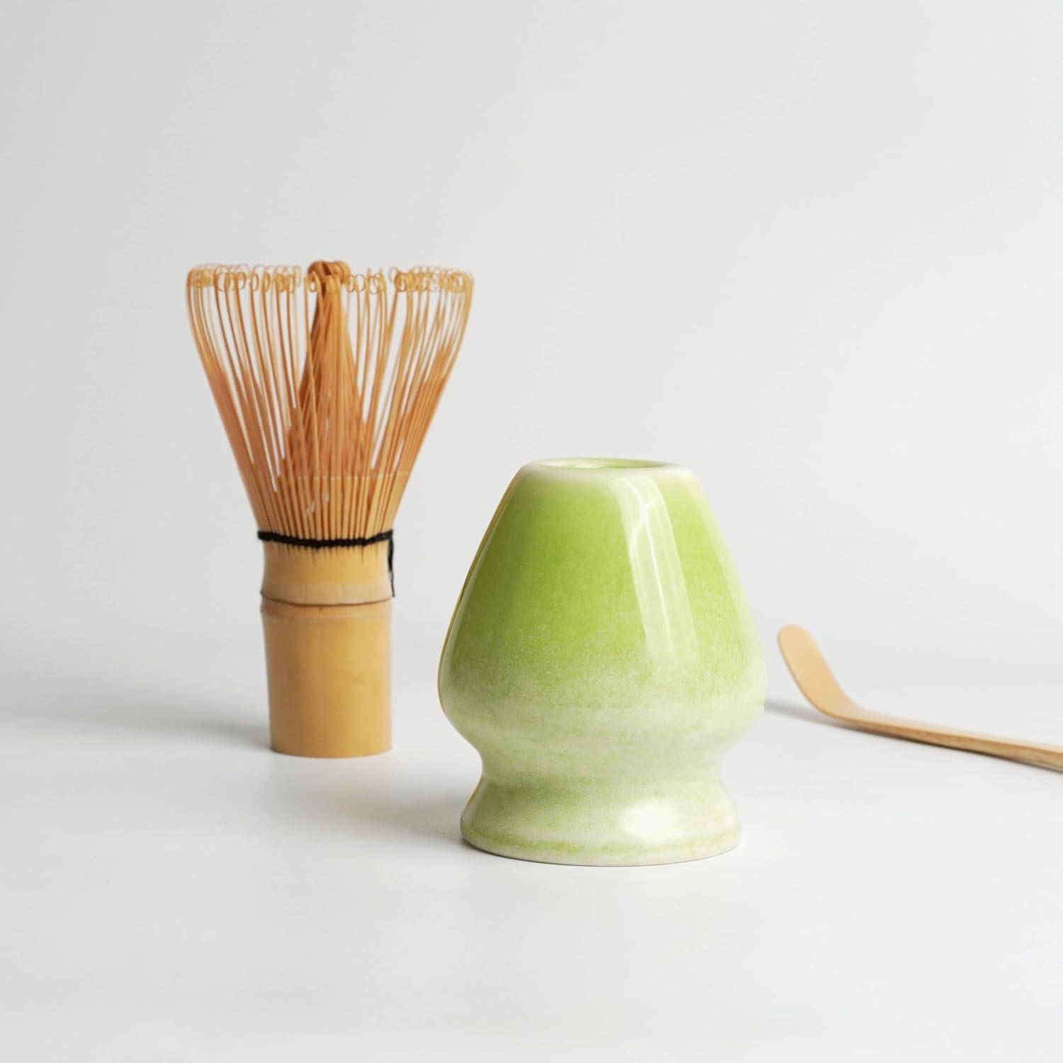 Grüne Keramik-Matcha-Schale, Bambusbesen und Löffel auf weißem Hintergrund.