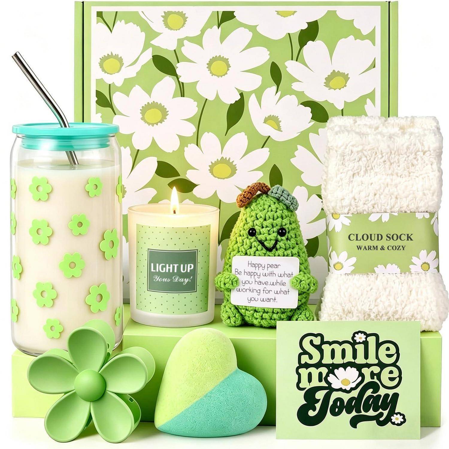 Ein frühlingsorientiertes Geschenkset mit einer Schachtel im Gänseblümchen-Muster, einem Mason-Jar-Trinkbecher, einer brennenden Kerze, einer gehäkelten Birne mit einem Zitat, flauschigen Socken, Blumendekoration und einem herzförmigen Schwamm mit einer Karte mit der Aufschrift „Lächle heute mehr