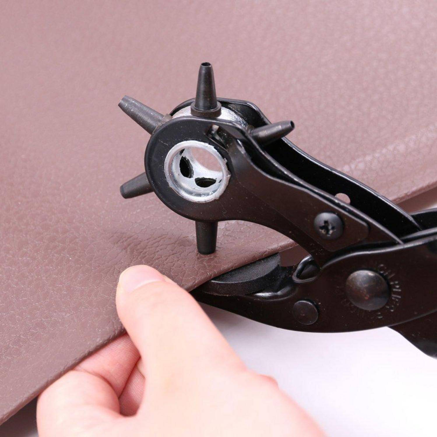 Tragbares Lederstanzwerkzeug, das ein Loch in braunes Material sticht, während ein Finger die Kante stabilisiert.