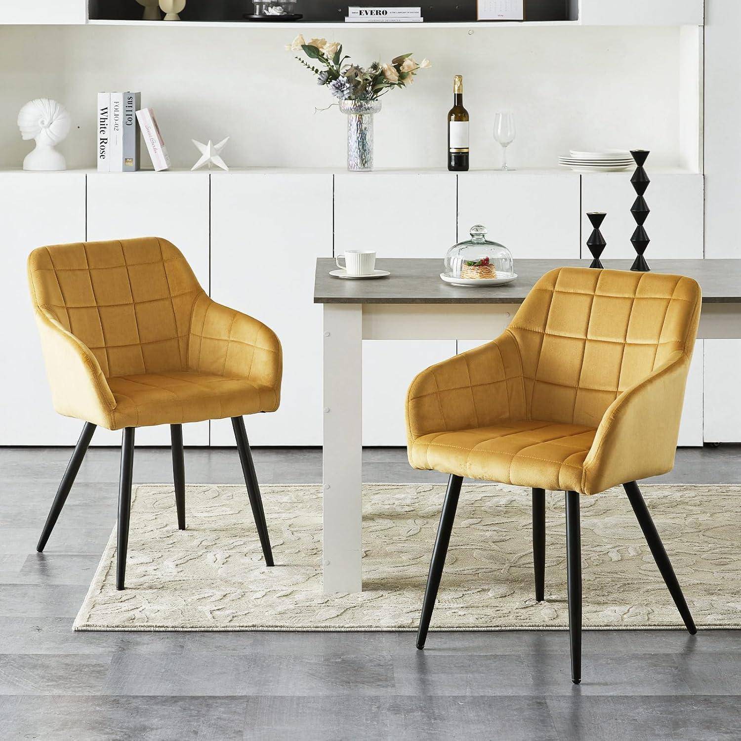 Zwei senfdgelb gepolsterte Esszimmerstühle neben einem kleinen Tisch in einem modernen weißen Esszimmer mit Schrankdekoration.