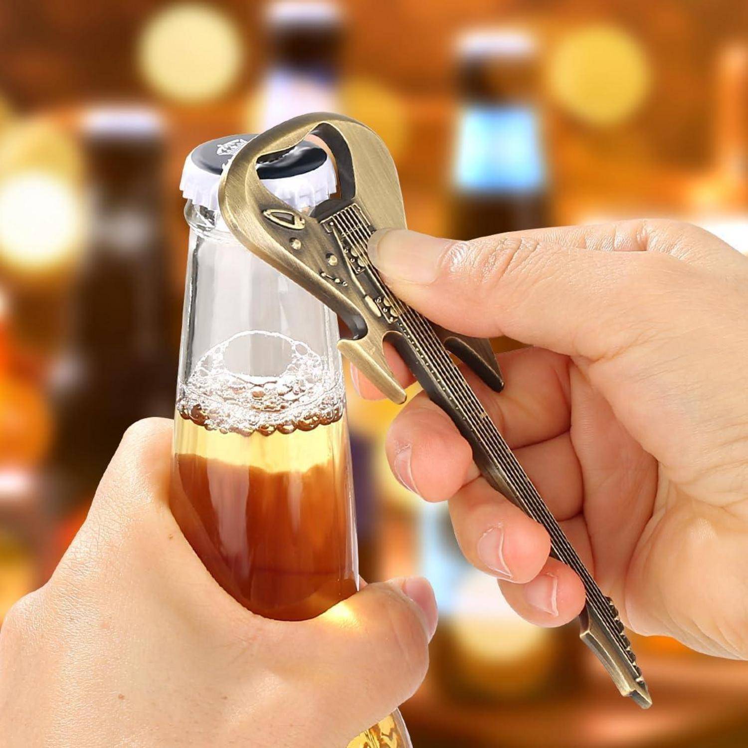 Hände benutzen ein Flaschenöffner-Werkzeug, um einen Metallverschluss von einer Glaskamera mit bernsteinfarbenem Bier abzuhebeln.