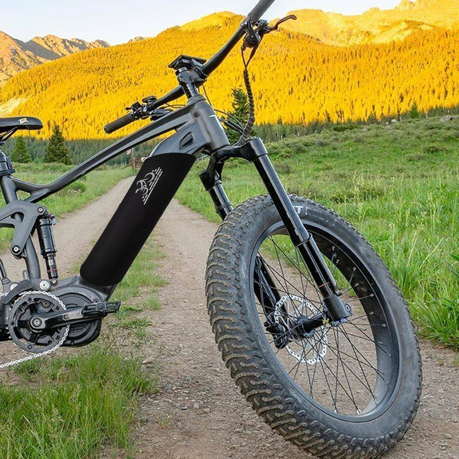 Schwarzes Elektro-Mountainbike mit breiten Reifen auf einem Feldweg mit Bergen und goldenen Bäumen im Hintergrund.