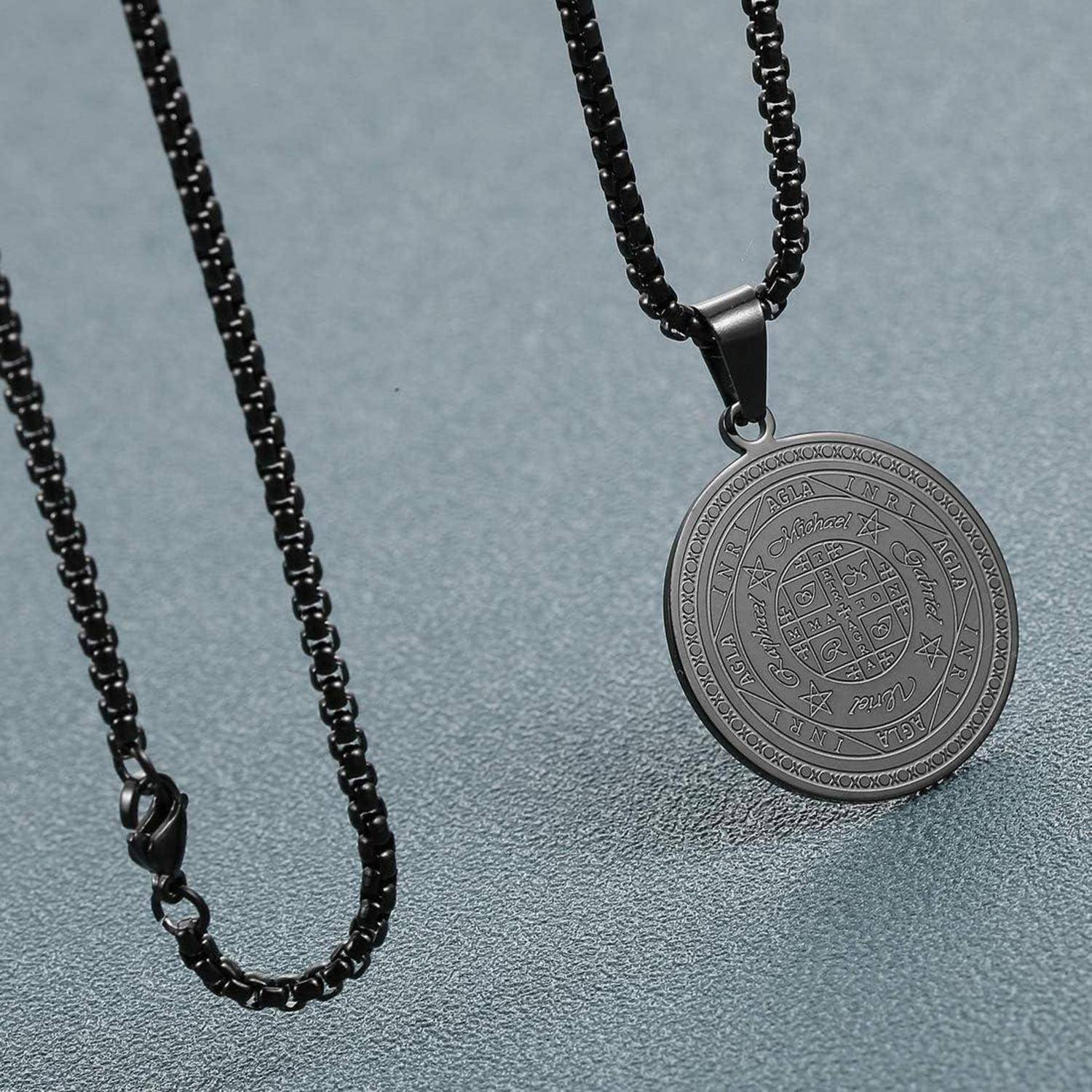 Schwarze Kettenkette mit rundem graviertem Metallanhänger auf grauem Hintergrund.