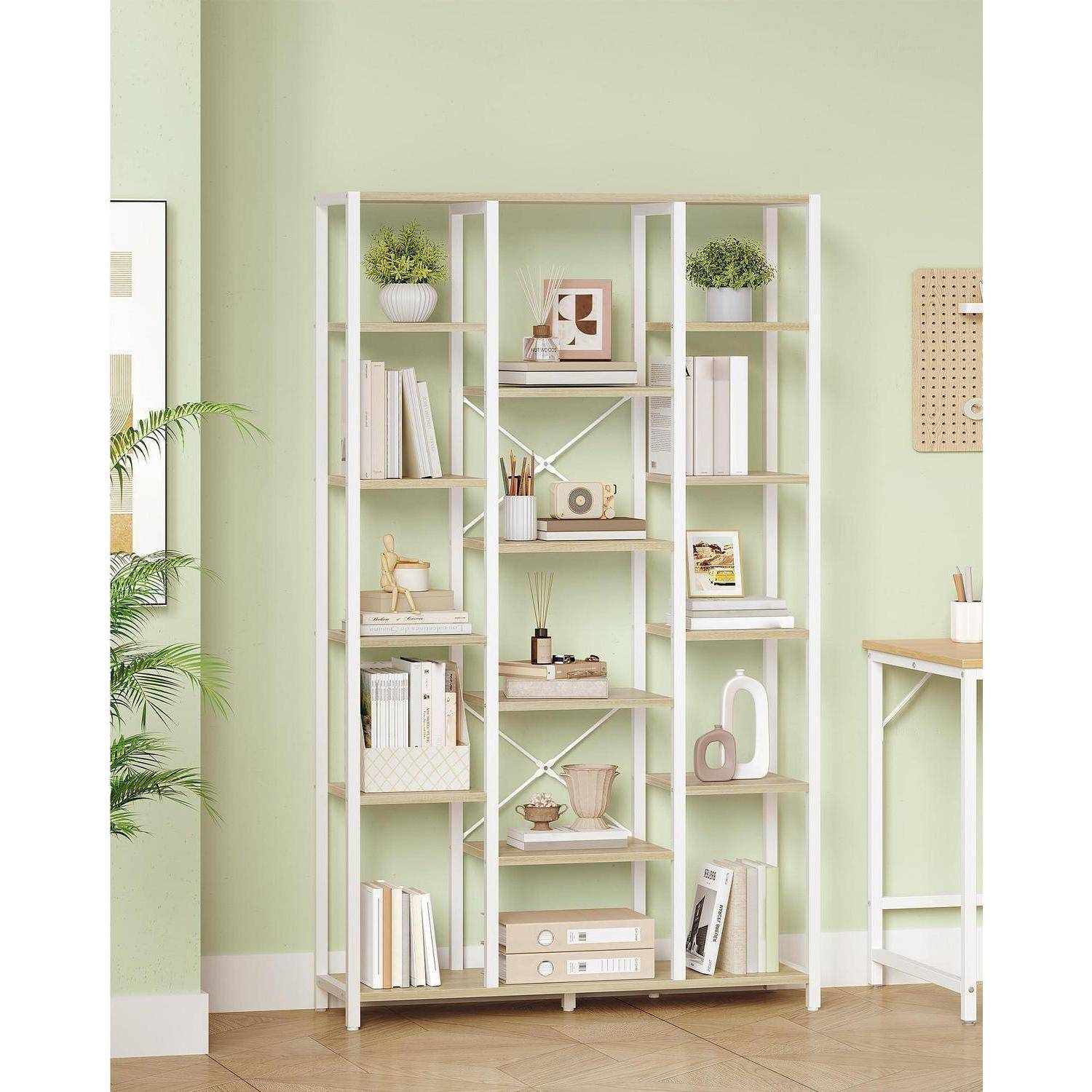 Offenes Bücherregal in Weiß mit Büchern, Pflanzen und Dekoration vor einer hellgrünen Wand in einem aufgeräumten Homeoffice oder Wohnzimmer.