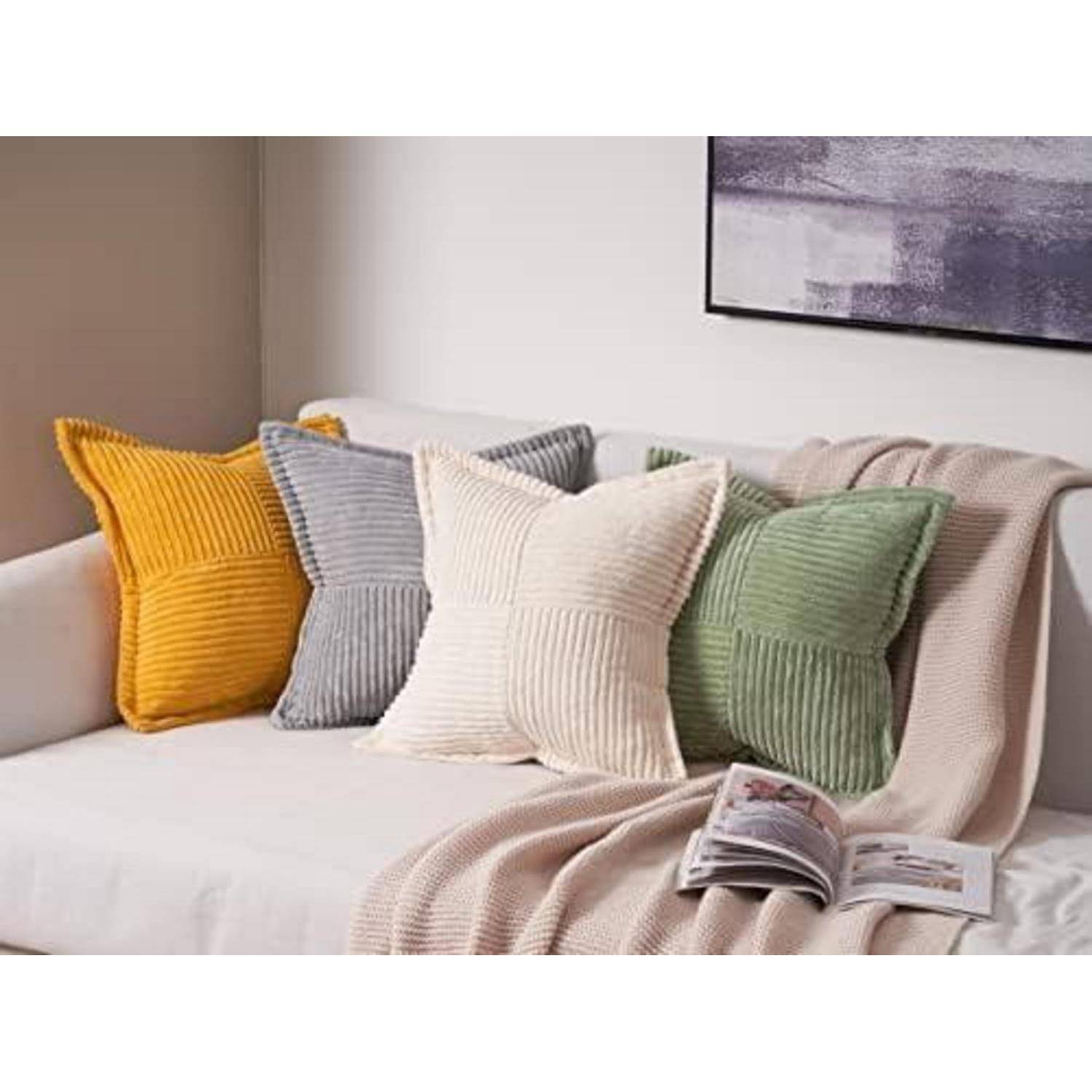 Ein sauber gestaltetes Sofa mit bunten strukturierten Wurfkissen, einer beigefarbenen Decke und einem offenen Magazin, das eine gemütliche Wohnzimmeratmosphäre schafft.