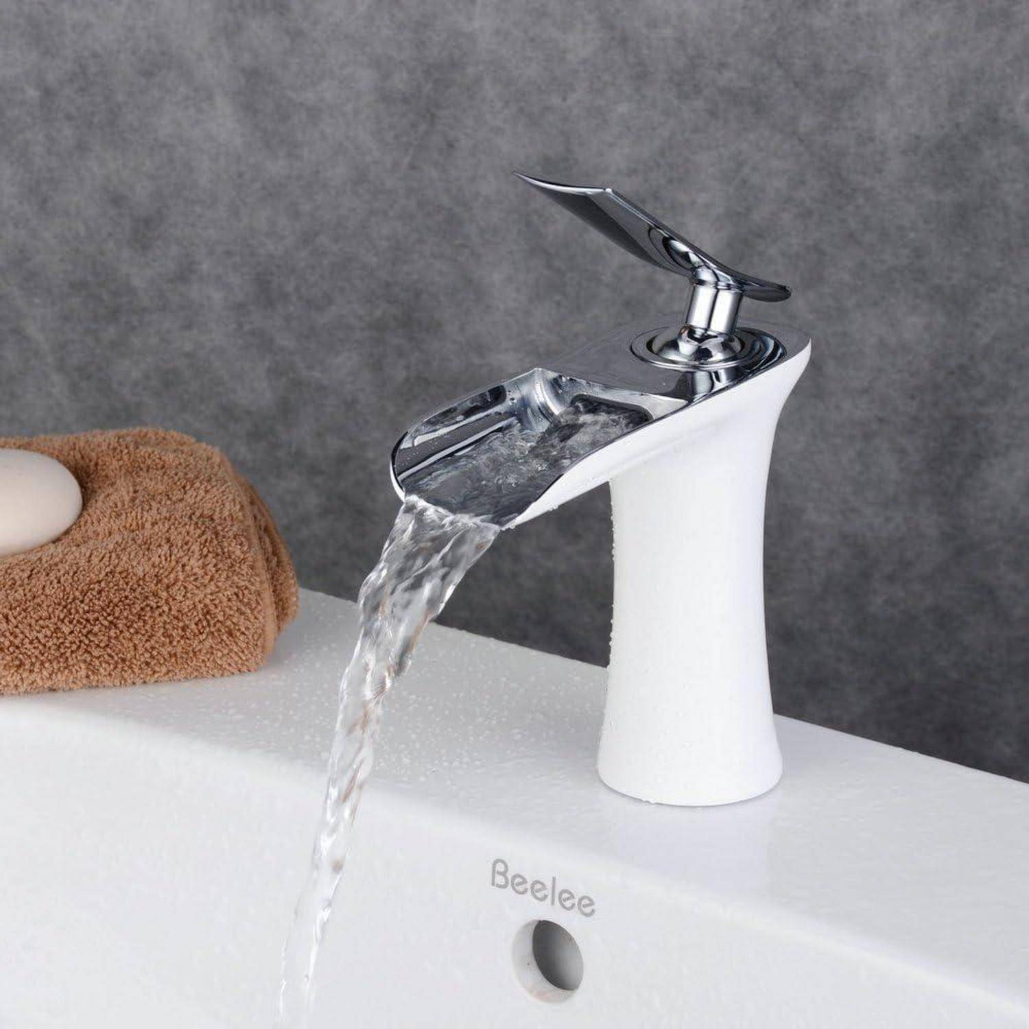 Moderner weißer Badezimmerhahn gießt Wasser über ein Waschbecken, mit einem braunen Handtuch auf der linken Seite und 