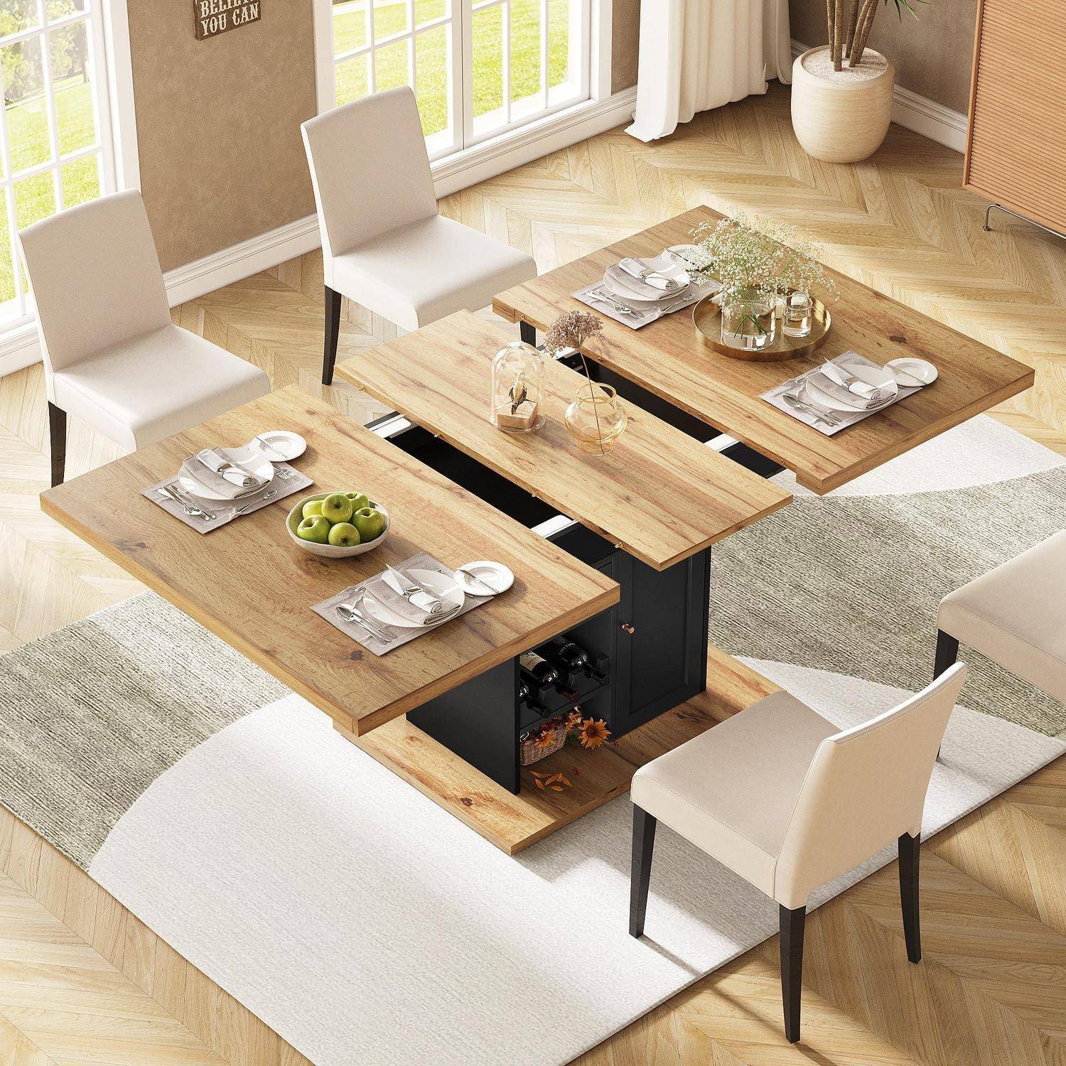 Ein moderner Couchtisch mit Hubplattform in einem hellen Ess-/Wohnzimmer, eingedeckt mit Tellern, Gläsern und einer Schüssel mit grünen Äpfeln, umgeben von weißen Stühlen und Teppichen.