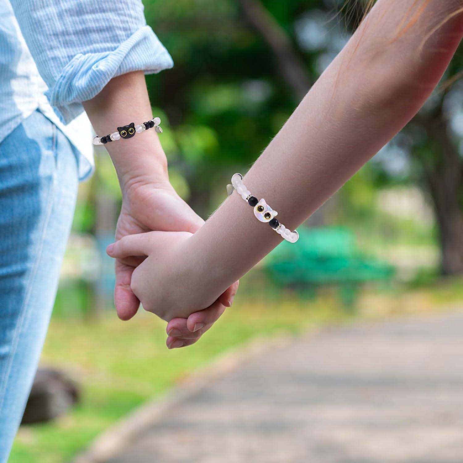 Zwei Kinder halten sich draußen an den Händen, jedes trägt ein passendes Eule-Perlen-Armband.