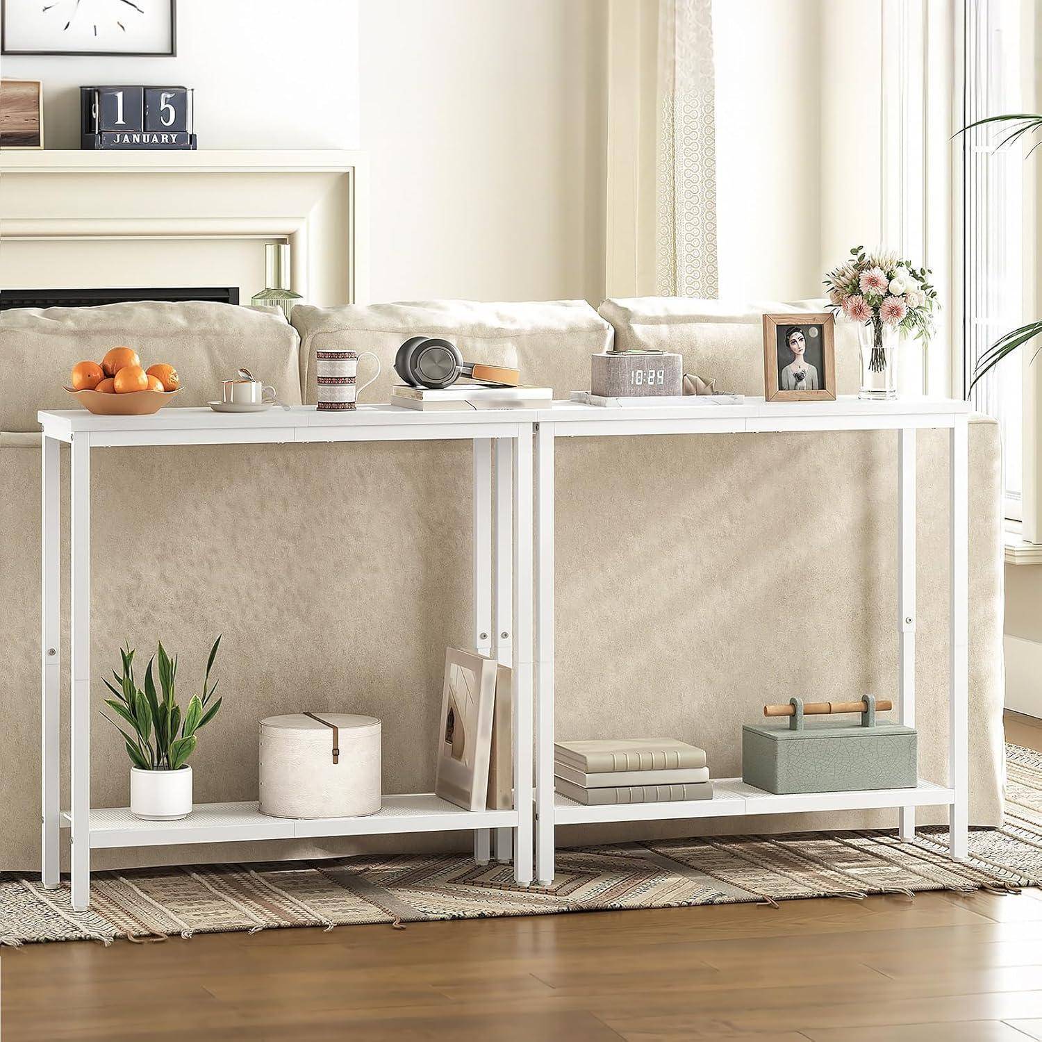 Zwei weiße Konsolentische hinter einem Sofa halten Obst, eine Uhr, eine Kamera, Blumen und Dekoration in einem hellen Wohnzimmer.