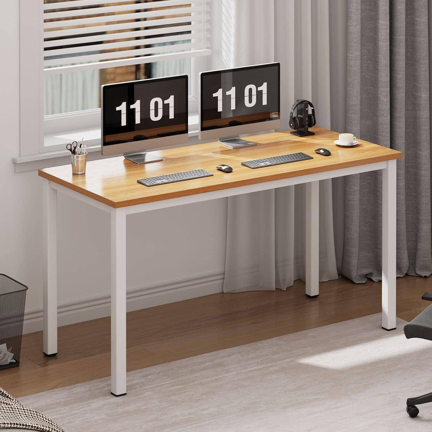 Moderner Stehschreibtisch an einem Fenster mit zwei Computermonitoren, Tastaturen, Maus, Kopfhörern und einer Kaffeetasse in einem Homeoffice.